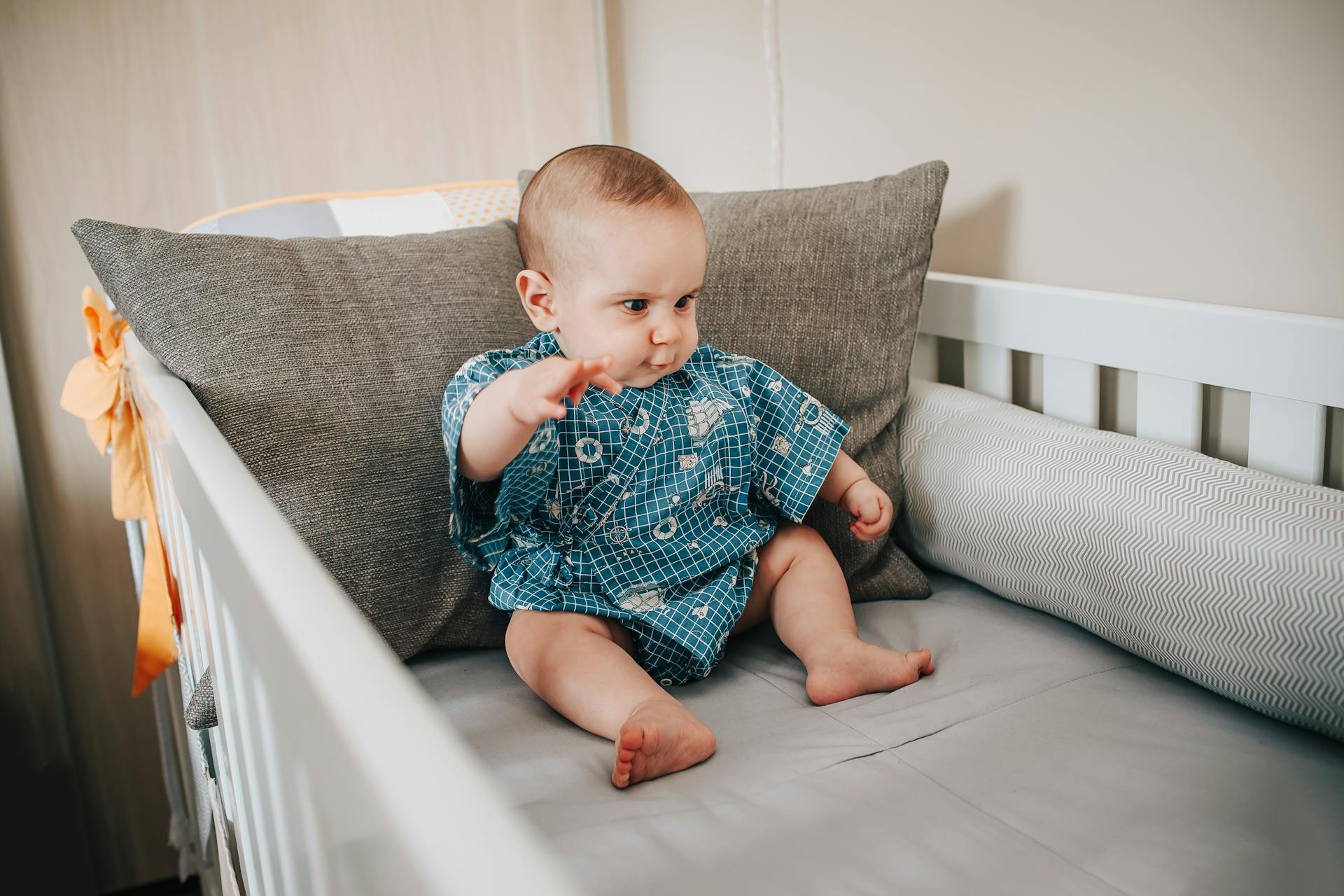 Ein Baby sitzt in einem Kinderbett | Quelle: Pexels