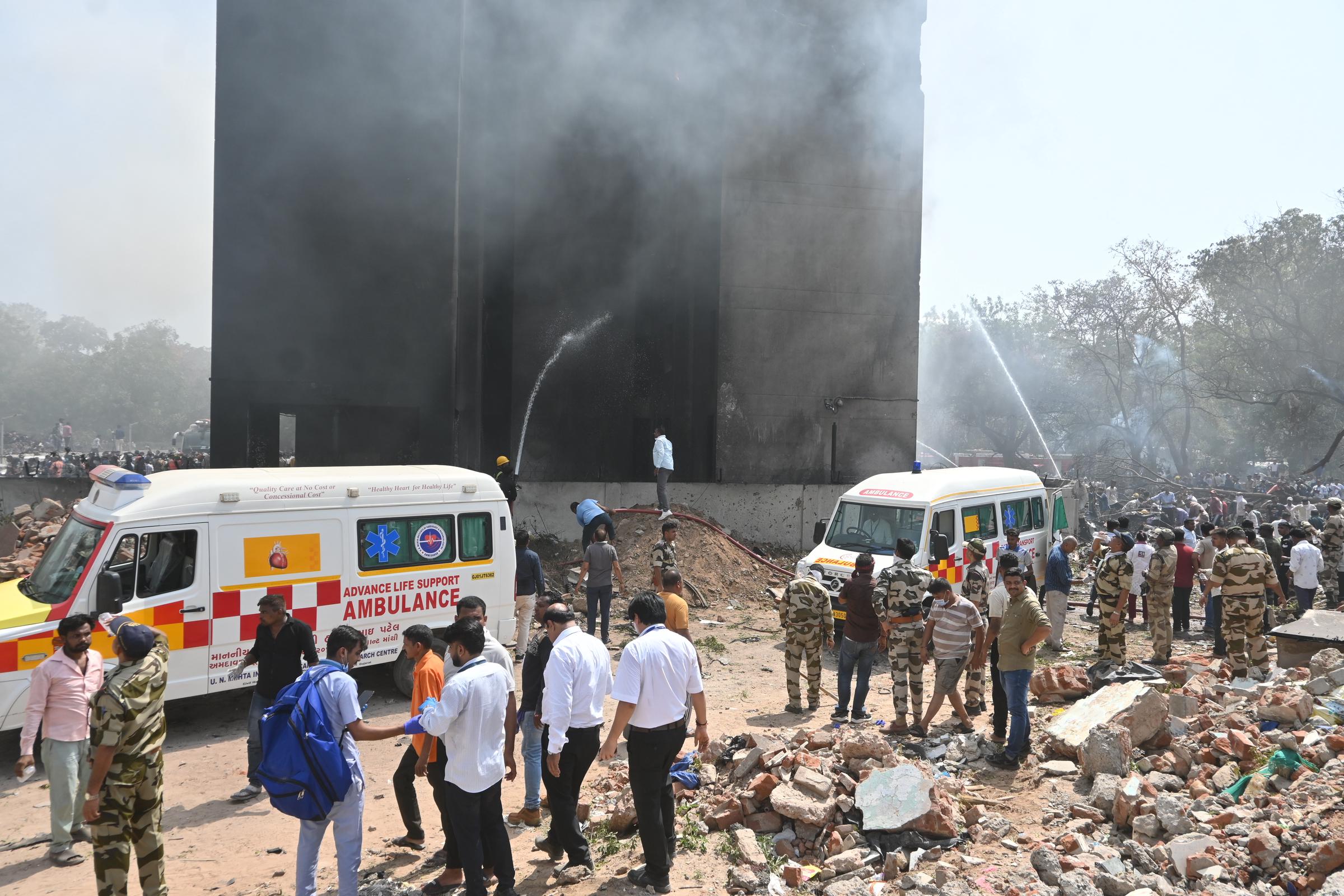 Rettungskräfte spritzen ein rauchgefülltes Gebäude ab, während sich Einsatzkräfte und Krankenwagen am 12. Juni 2025 an der Absturzstelle in Ahmedabad versammeln | Quelle: Getty Images
