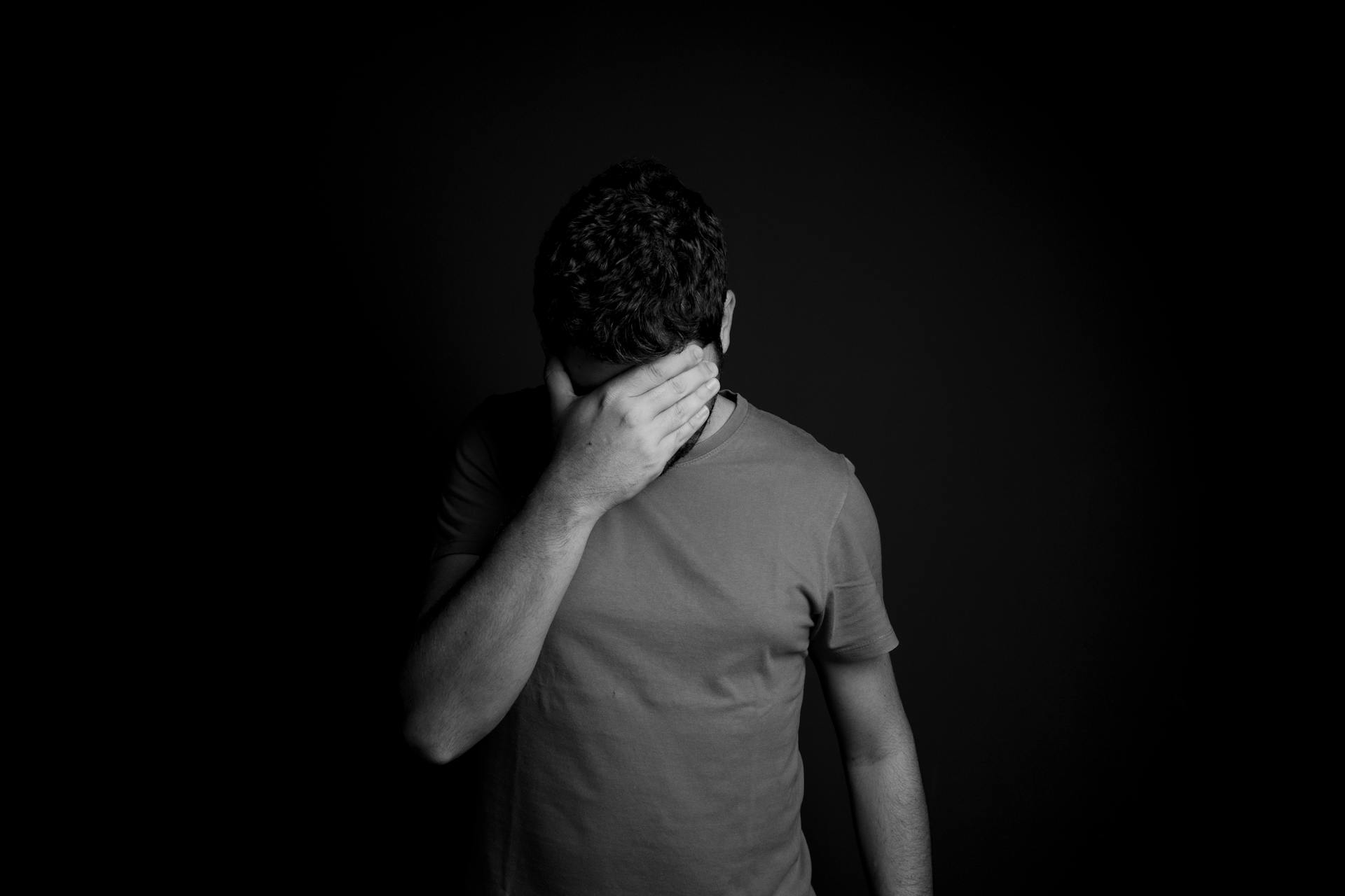 Ein Graustufenfoto eines traurigen Mannes, der sein Gesicht mit der Hand bedeckt | Quelle: Pexels