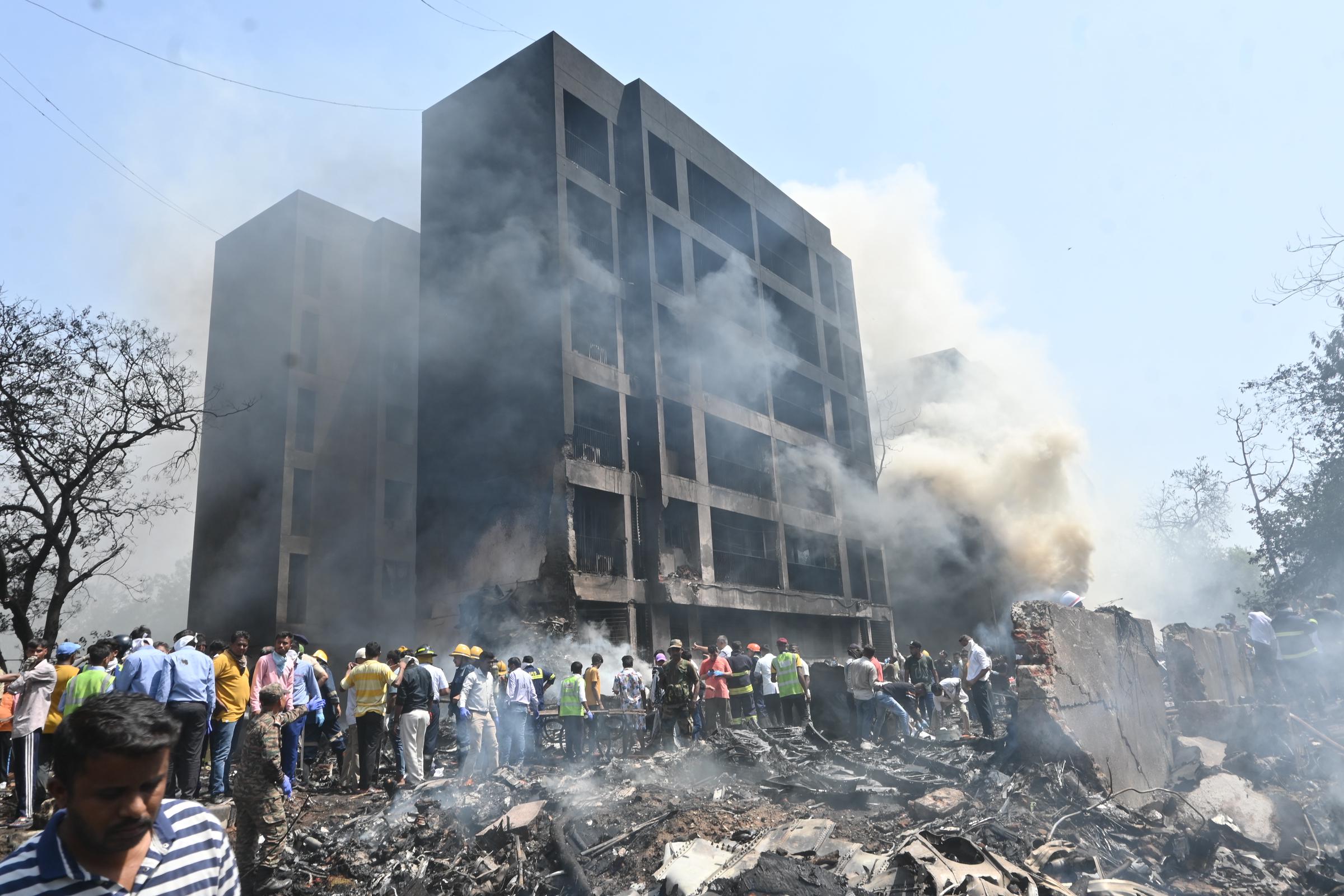 Rauch steigt aus einem beschädigten Gebäude auf, während sich Menschen an der Absturzstelle in Ahmedabad, Indien, am 12. Juni 2025 versammeln: Getty Images