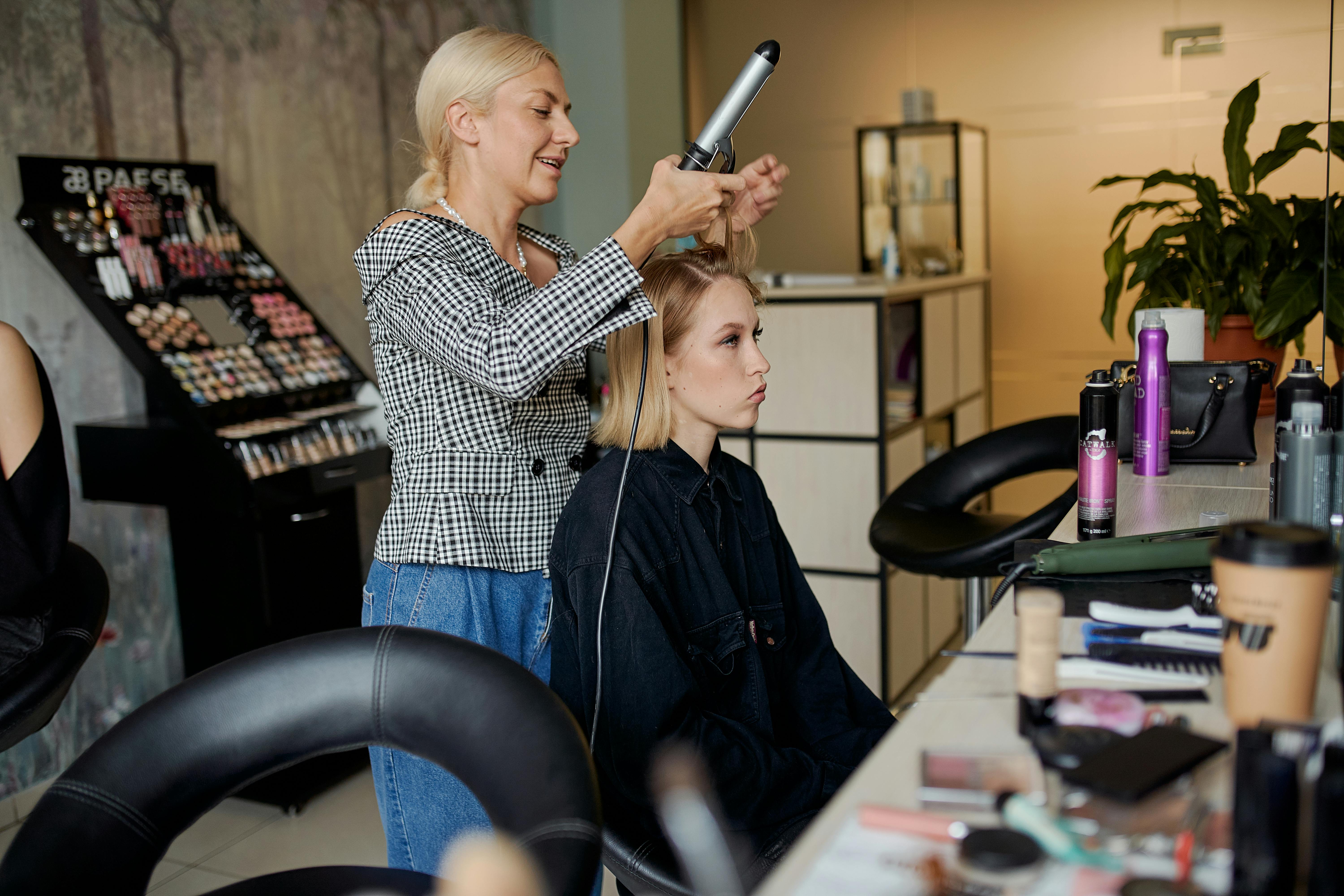 Eine Friseurin glättet das Haar eines Kunden | Quelle: Pexels