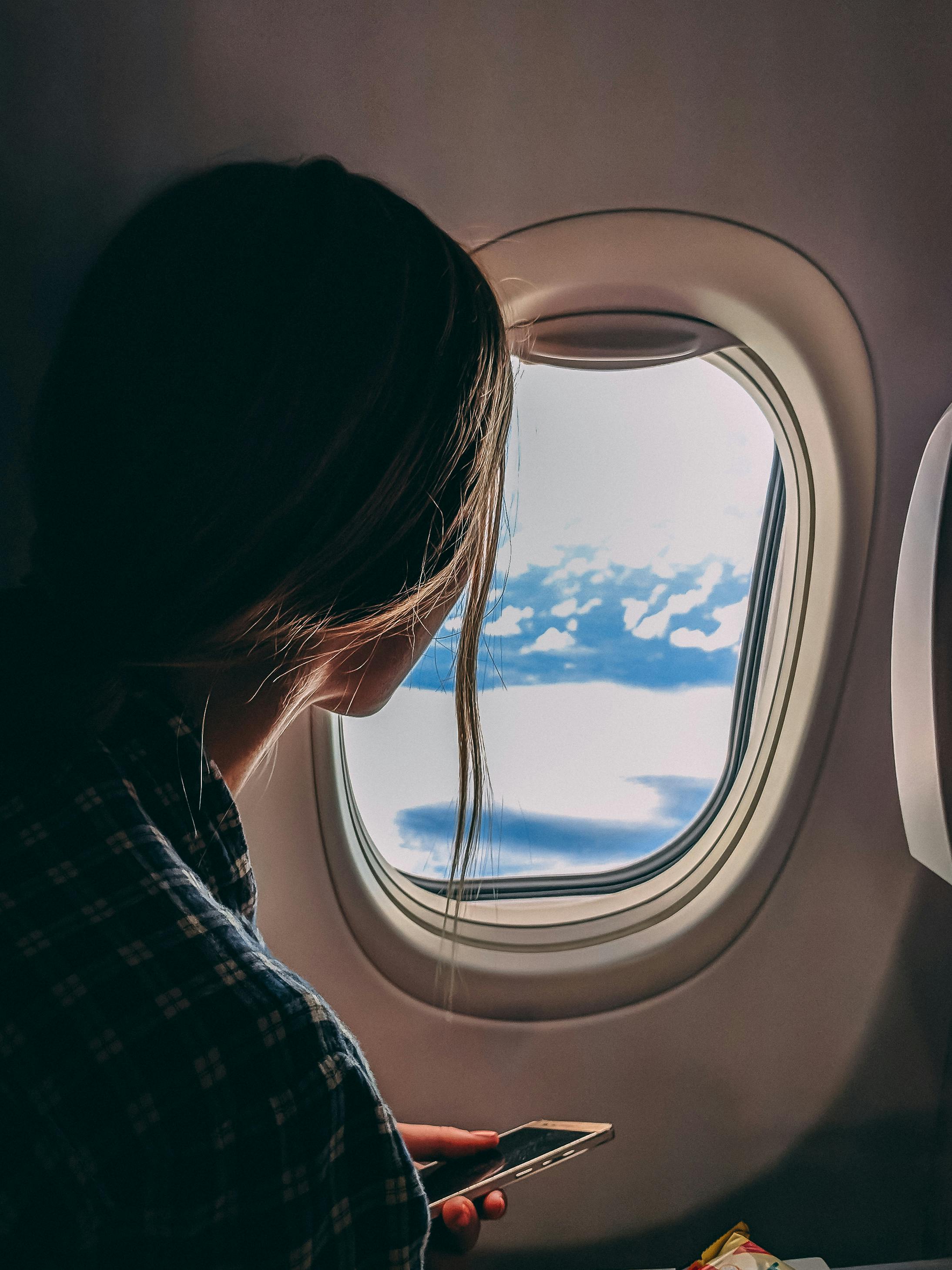 Eine Frau, die aus dem Fenster eines Flugzeugs schaut | Quelle: Pexels