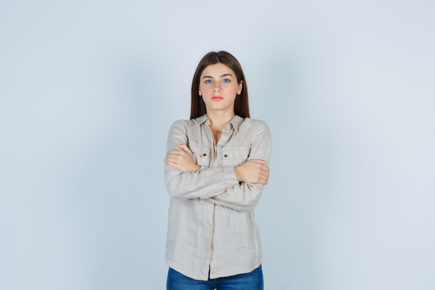 Eine junge Frau, die mit verschränkten Armen dasteht und starrt | Quelle: Freepik