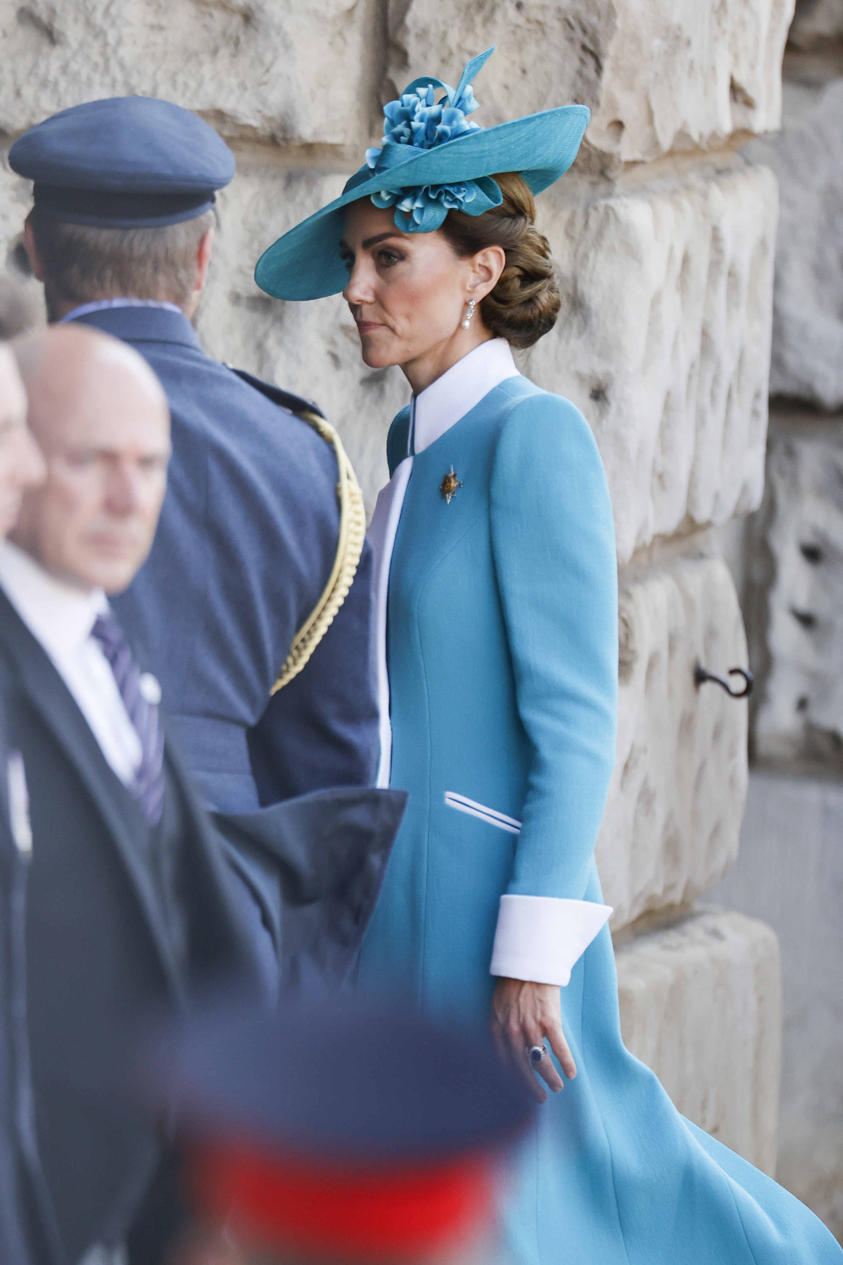 Eine Ganzseitenaufnahme fängt Prinzessin Catherines Trooping-the-Colour-Ensemble aus dem Jahr 2025 in beeindruckenden Details ein. Ihr maßgeschneiderter türkisfarbener Mantel mit den auffälligen weißen Manschetten und dem Kragen wird durch einen passenden, blumengeschmückten Hut ergänzt. Der Blickwinkel unterstreicht die raffinierten Linien ihres Outfits und die Eleganz ihrer Körperhaltung, während sie an den Feierlichkeiten teilnimmt.