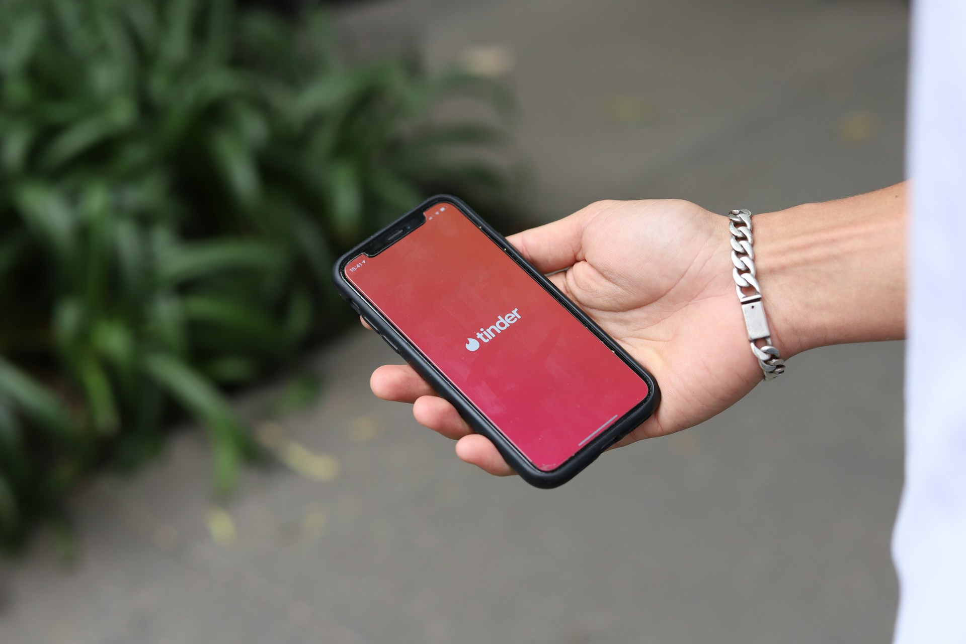 Ein Mann hält ein Handy, auf dem die Tinder-App angezeigt wird | Quelle: Unsplash