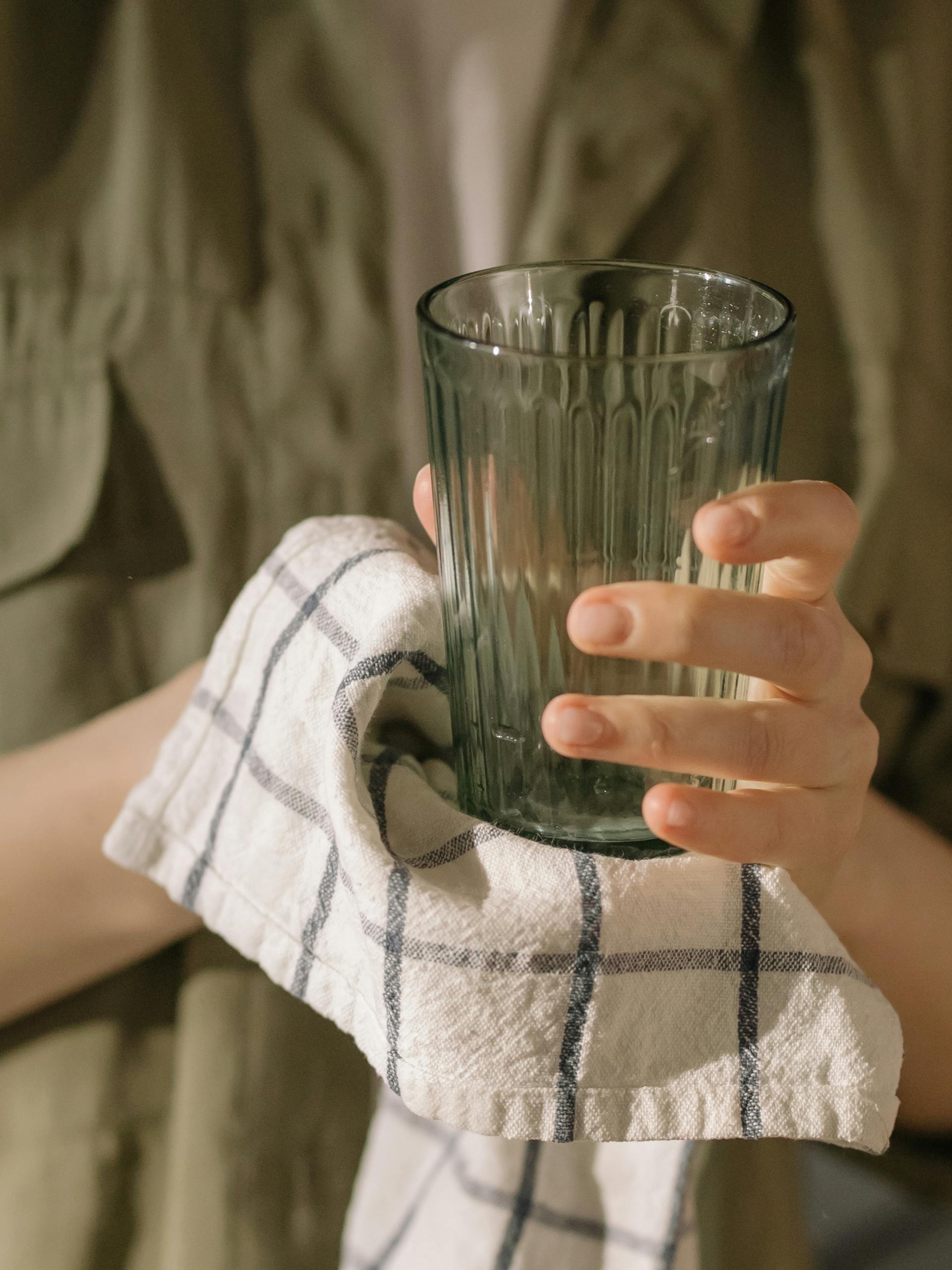 Eine Frau trocknet ein Glas mit einem Handtuch ab | Quelle: Pexels
