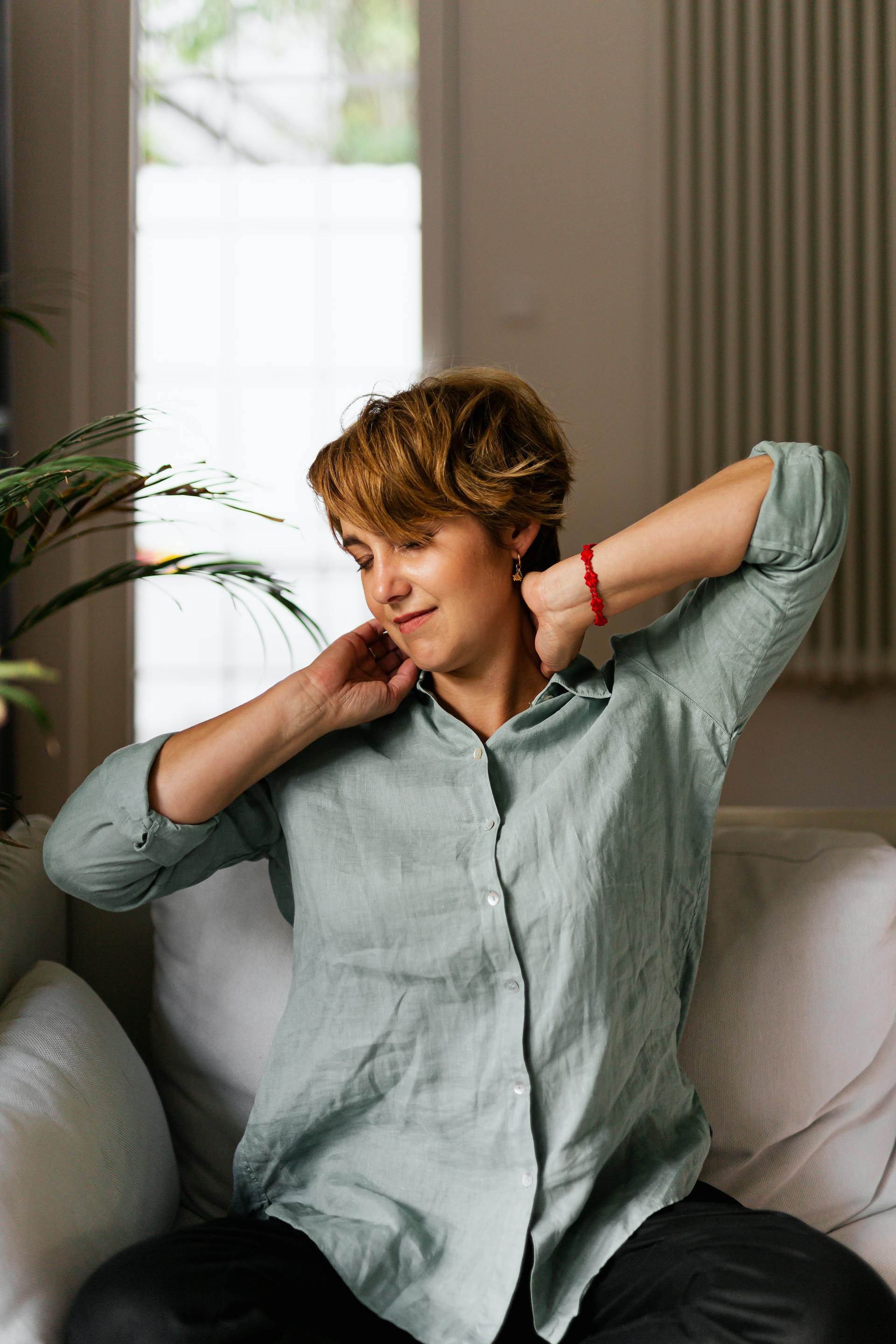 Eine Frau, die sich auf einer Couch sitzend dehnt | Quelle: Pexels