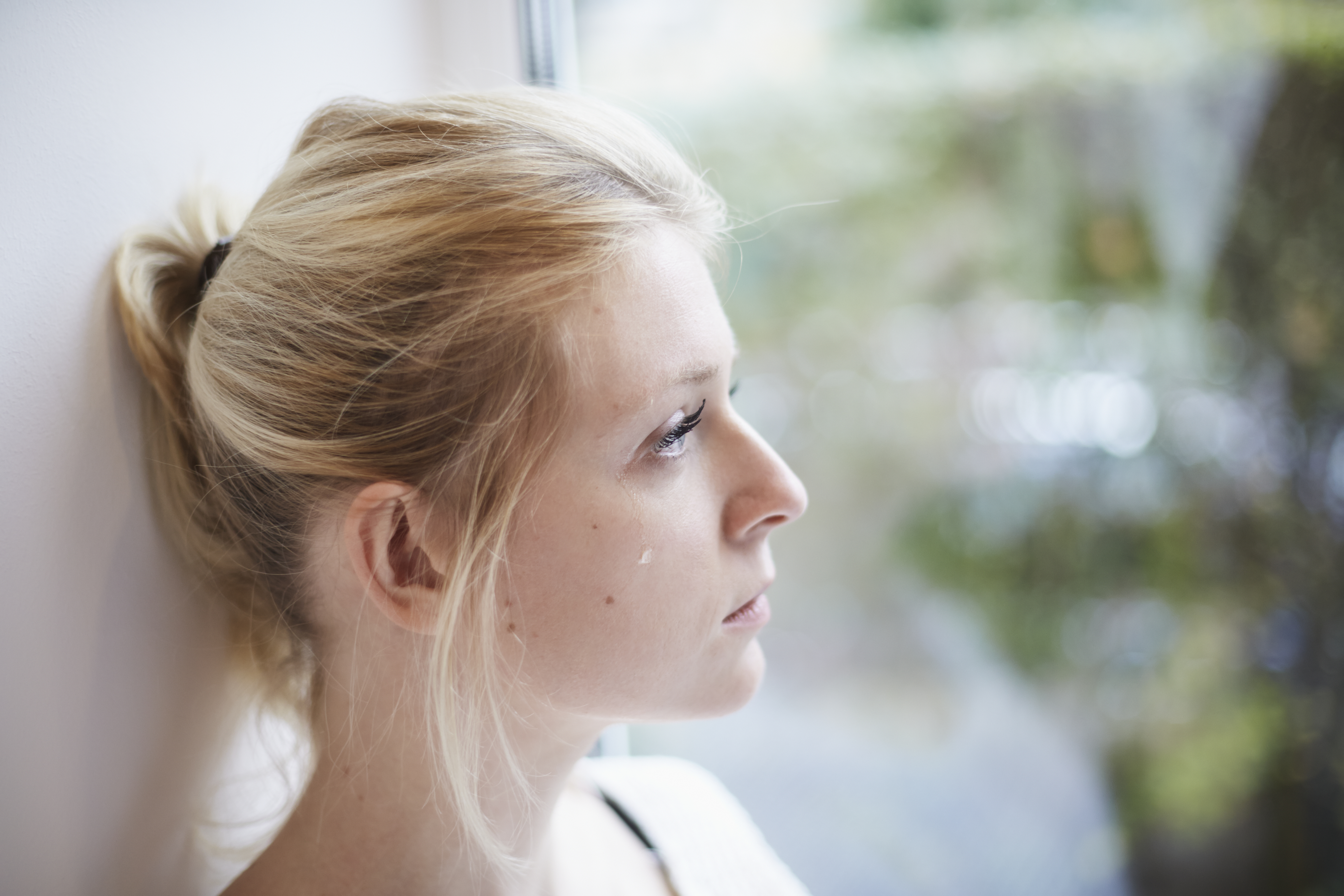 Junge Frau weint am Fenster | Quelle: Getty Images