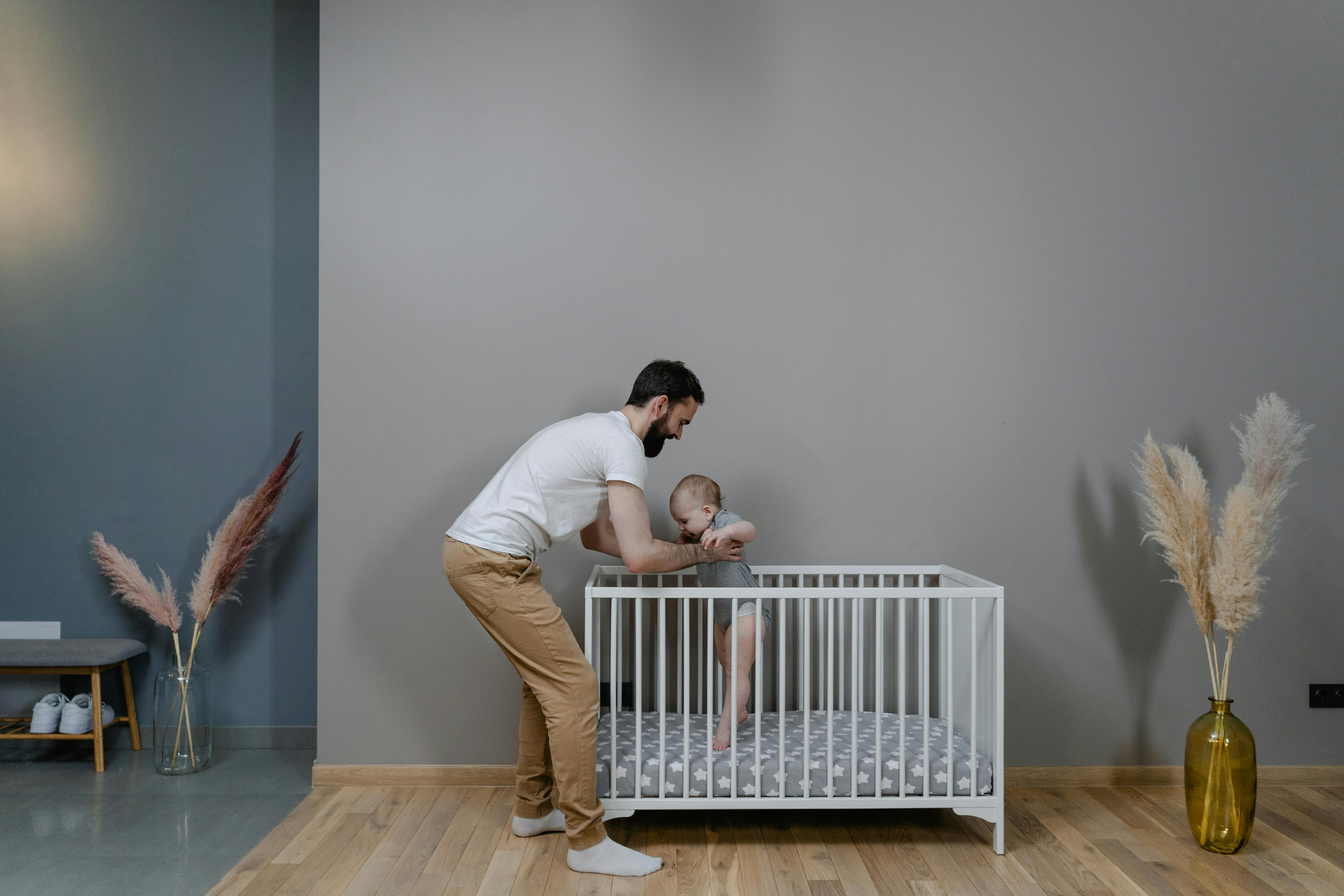 Ein Mann hält ein Baby in einer Krippe | Quelle: Pexels
