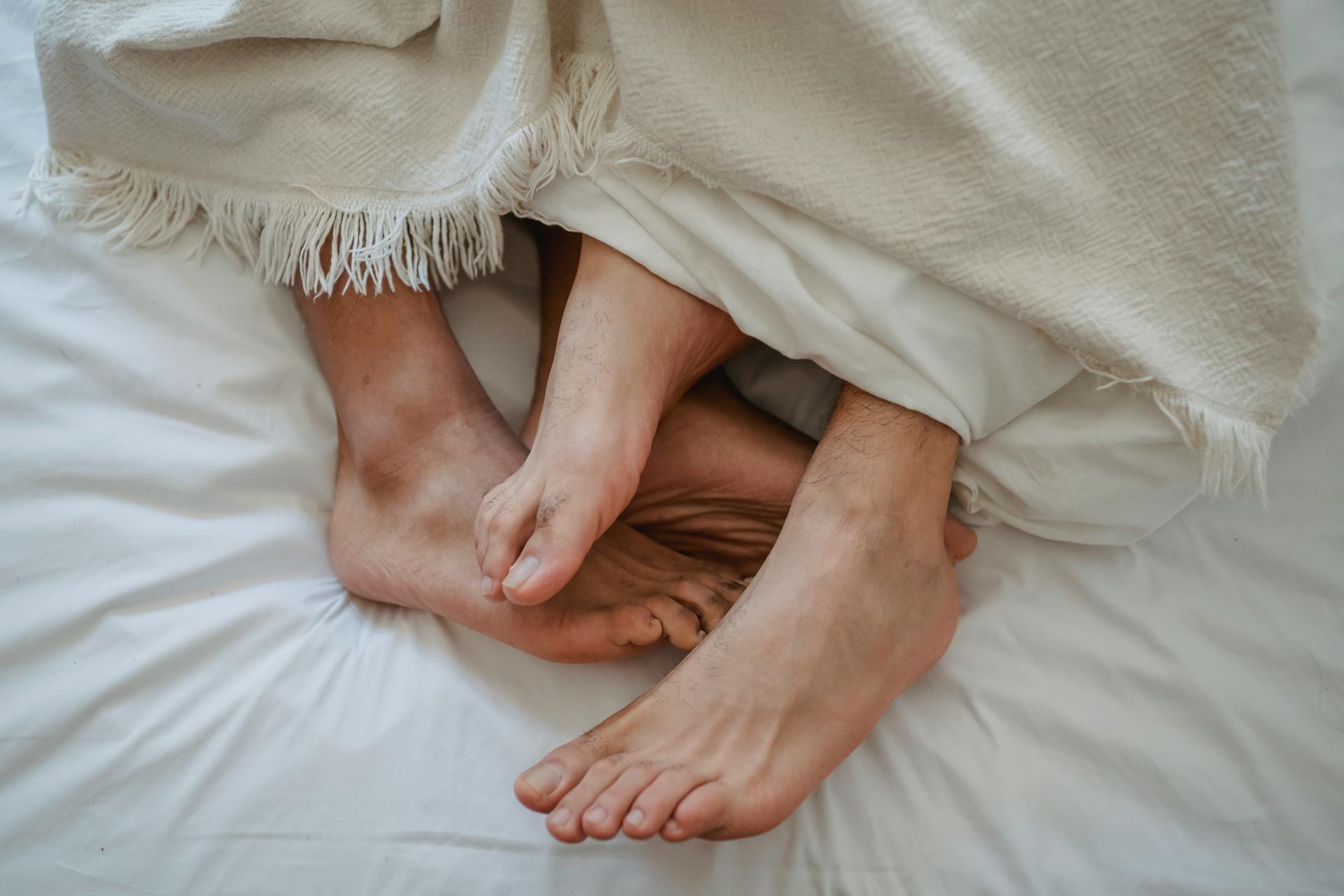 Füße von zwei Männern ineinander verschlungen im Bett | Quelle: Pexels