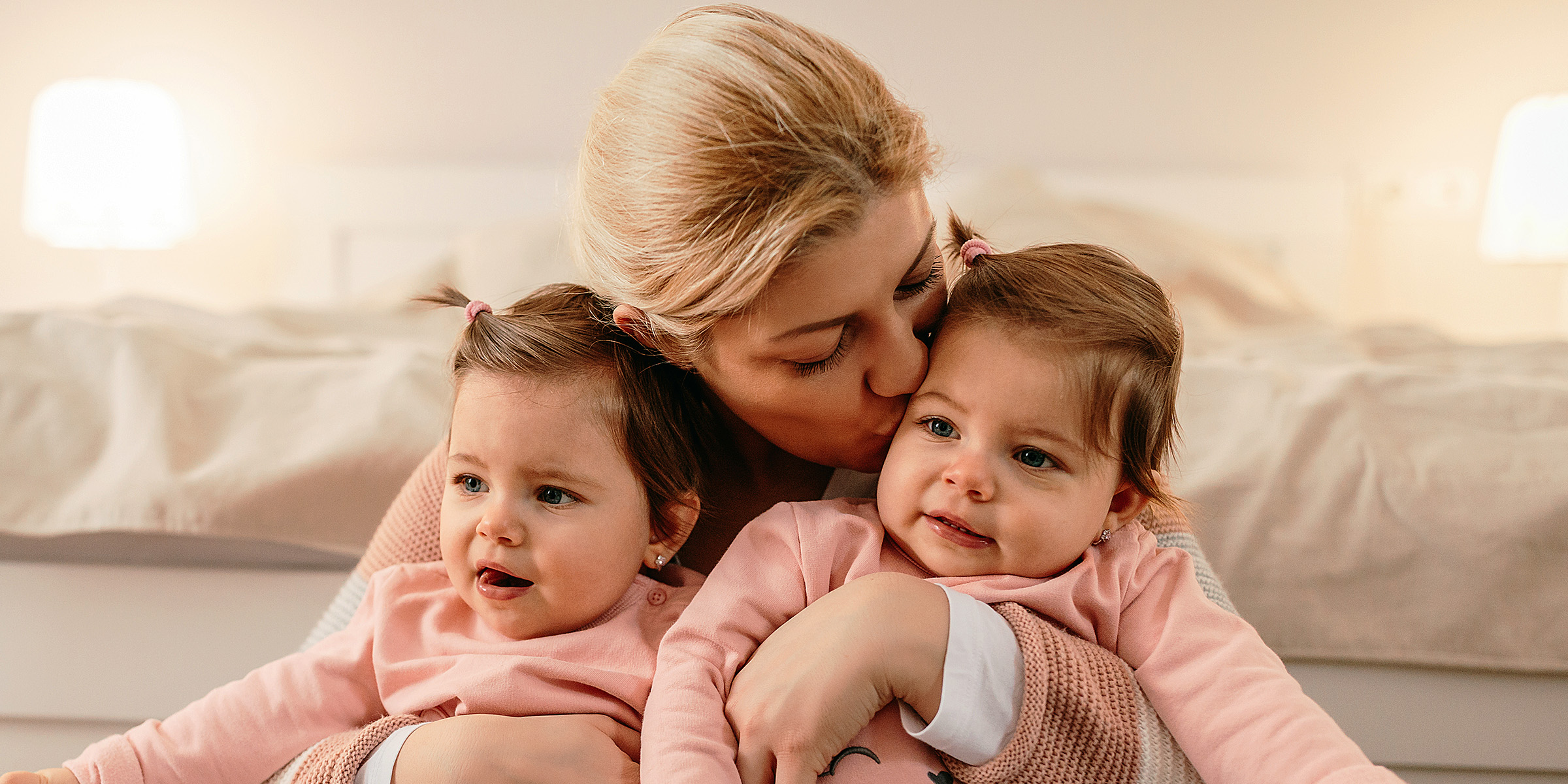 Eine Frau hält ihre Zwillingstöchter im Arm | Quelle: Shutterstock