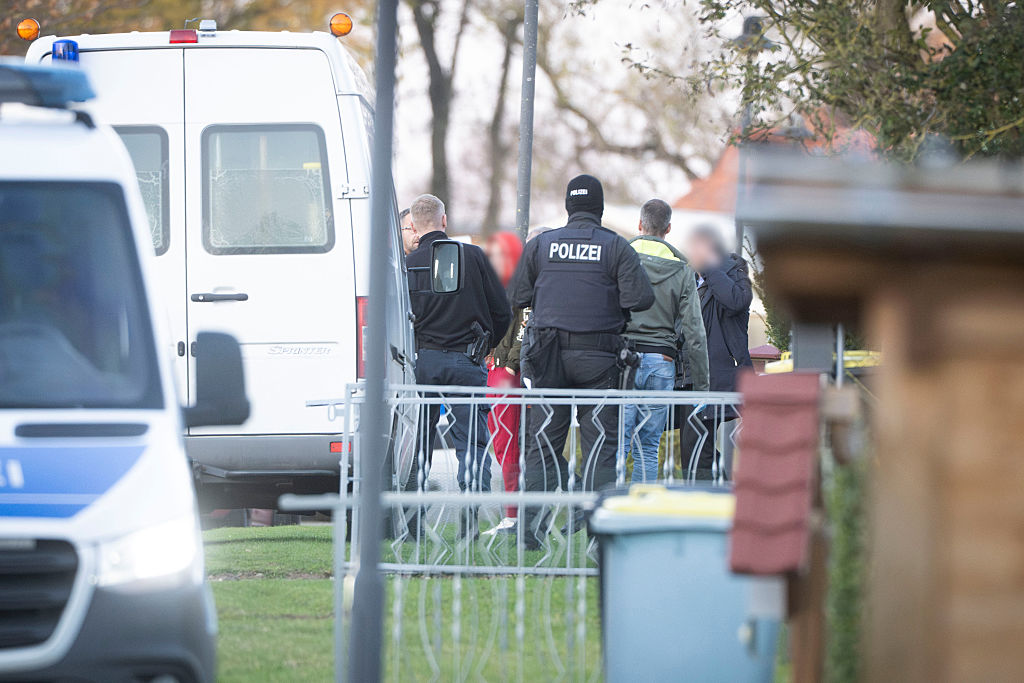 06. November 2025, Mecklenburg-Vorpommern, Güstrow: Eine Tatverdächtige (Mitte links) verlässt in Begleitung von Polizeibeamten ihre Wohnung. | Quelle: Getty Images