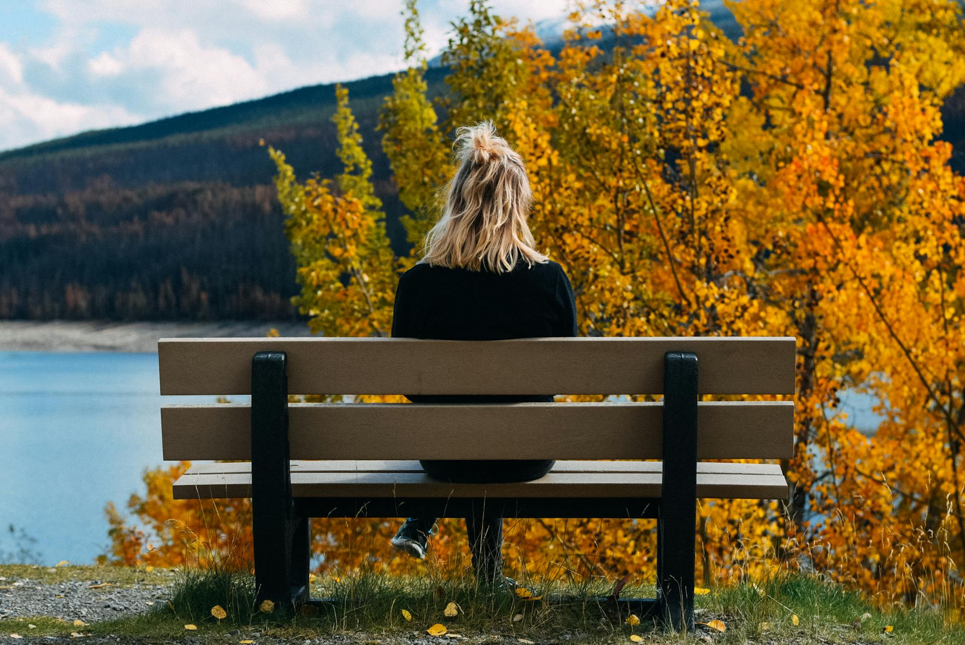 Eine Frau sitzt auf einer Bank und schaut auf den See | Quelle: Pexels