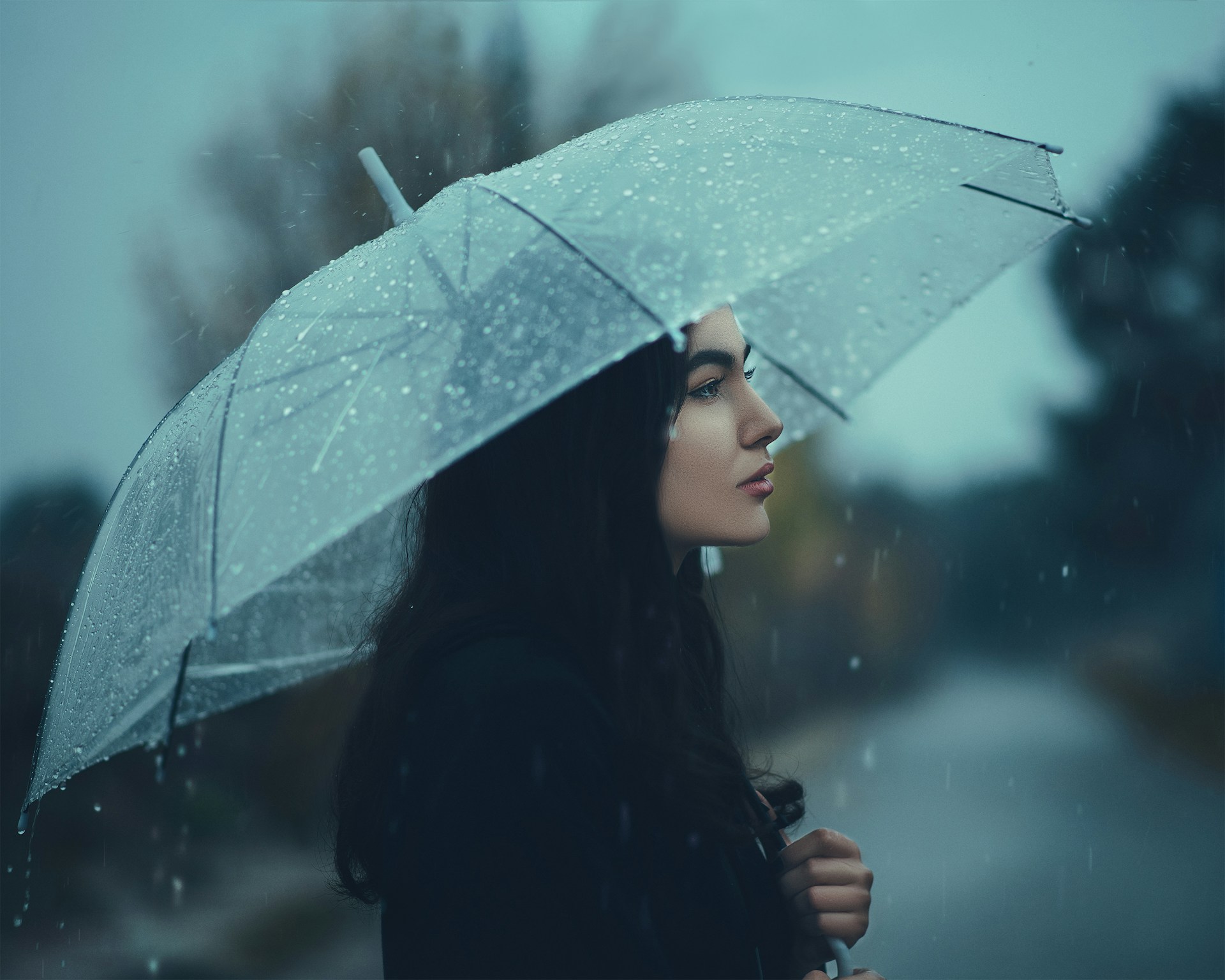 Eine Frau steht im Regen mit einem Regenschirm | Quelle: Unsplash
