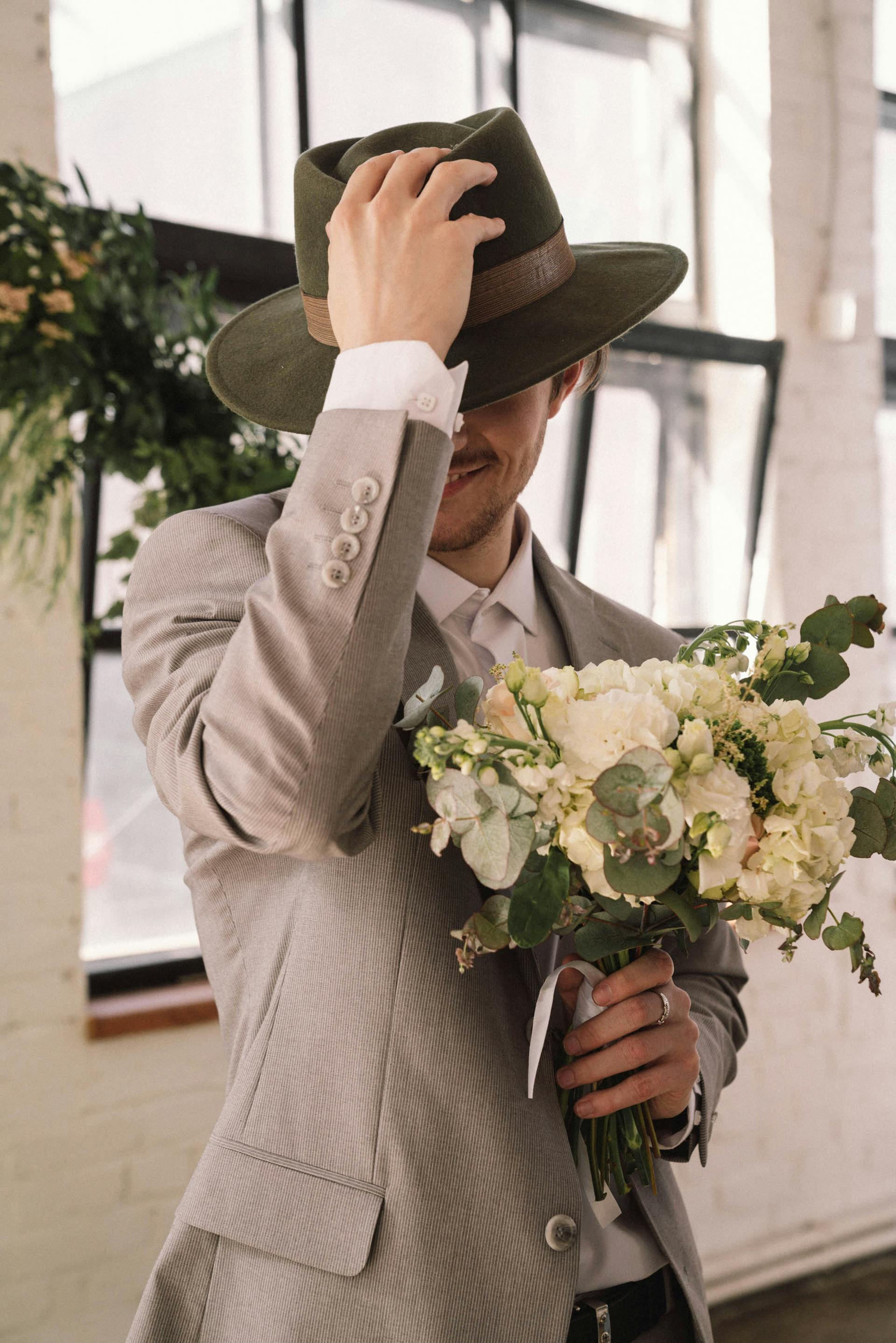 Mann in grauem Anzug und Hut hält Blumen | Quelle: Pexels