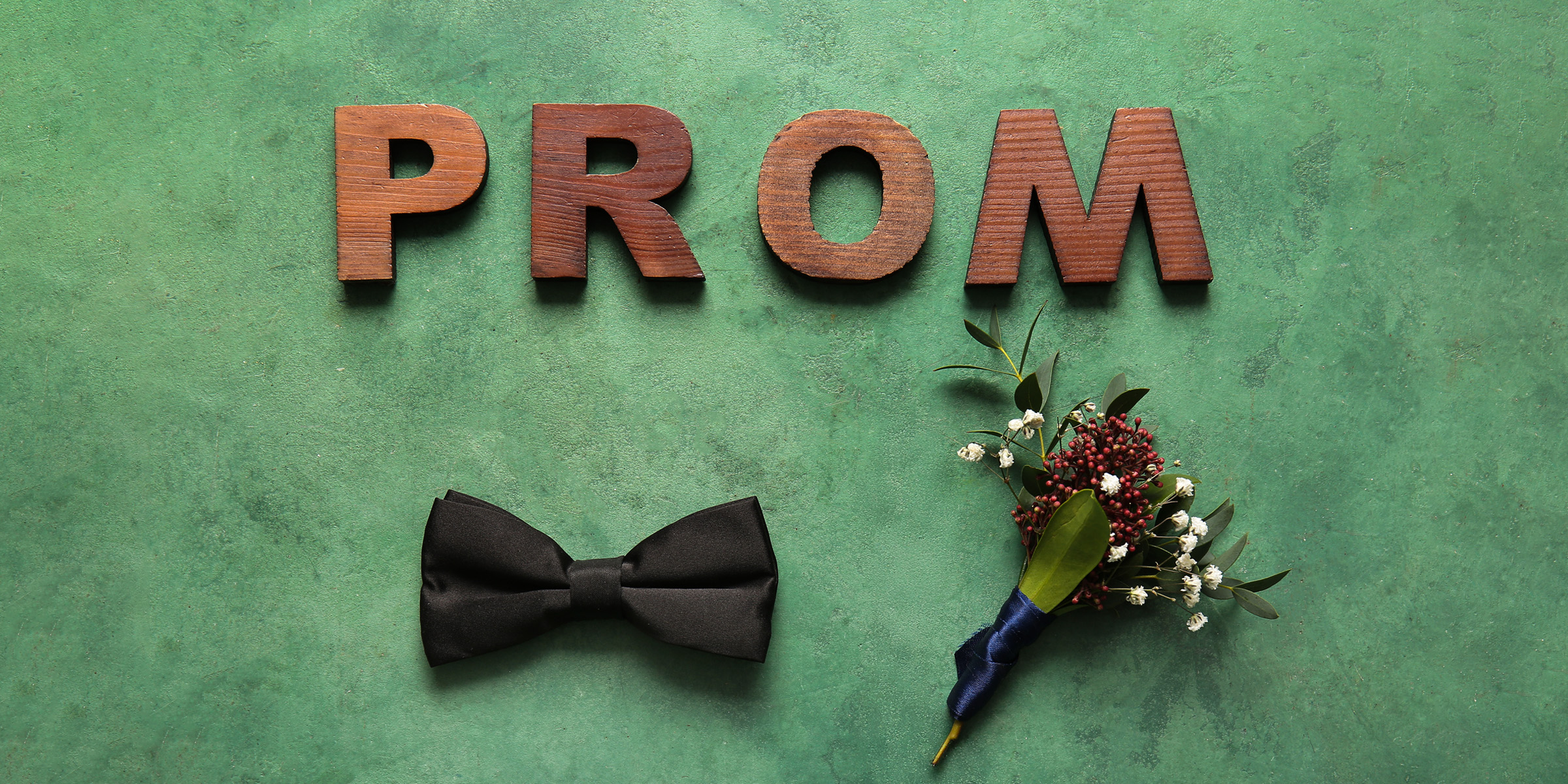 Buchstaben, die das Wort Prom ("Abschlussball") bilden, eine Fliege und ein Sträußchen | Quelle: Shutterstock