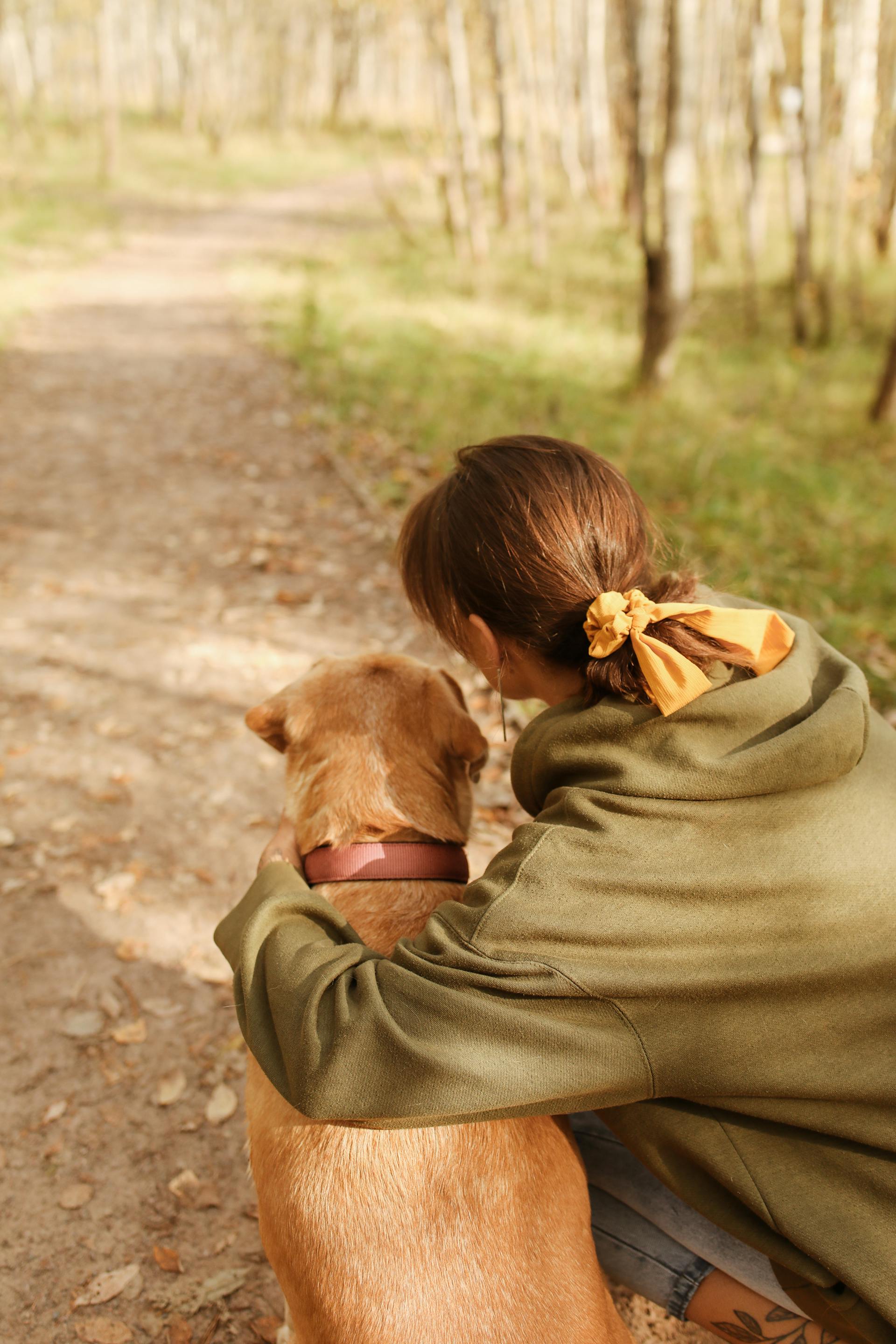 Eine Rückansicht einer Frau, die neben ihrem Hund kniet | Quelle: Pexels