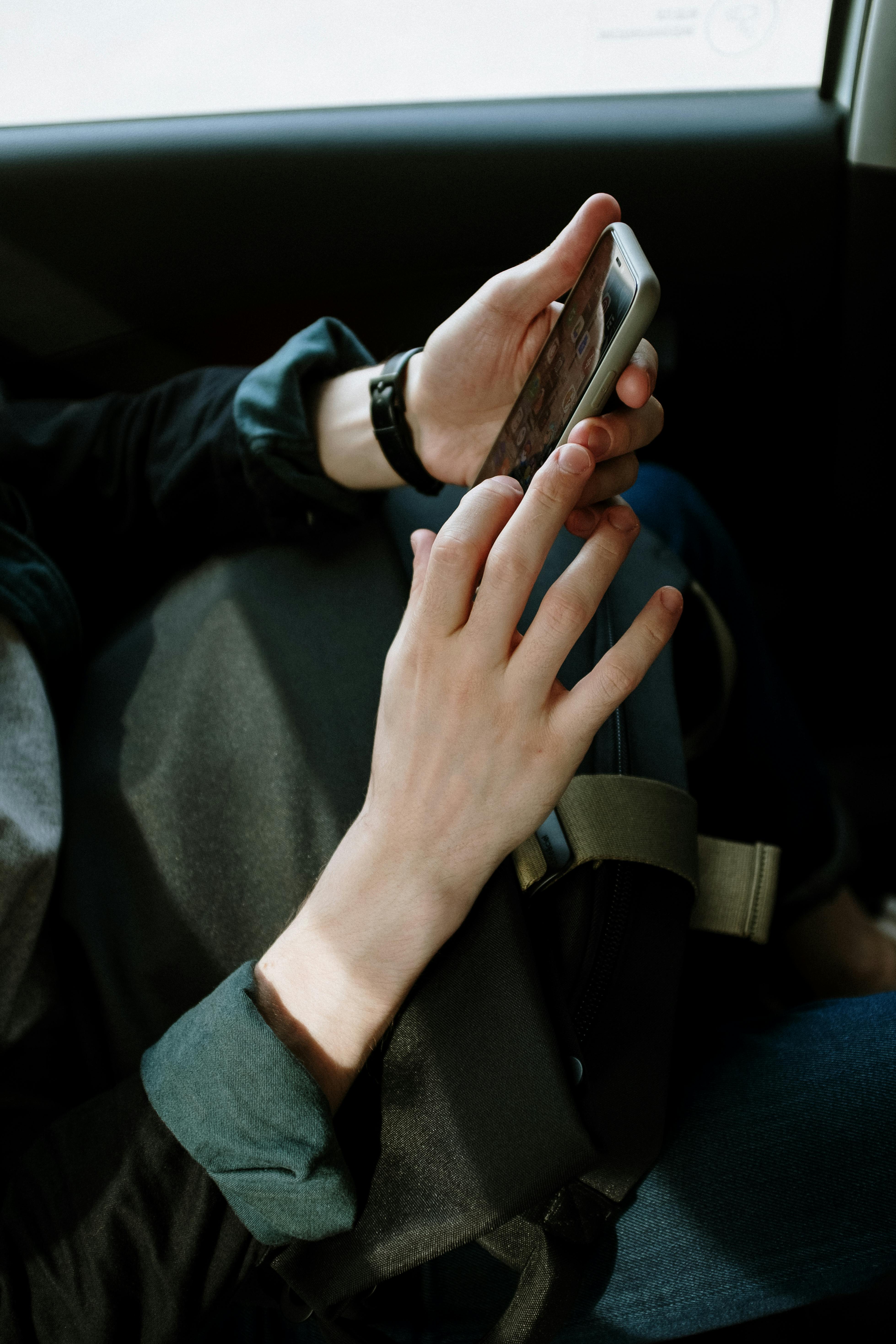 Eine Person hält ein Mobiltelefon in einem Auto | Quelle: Pexels