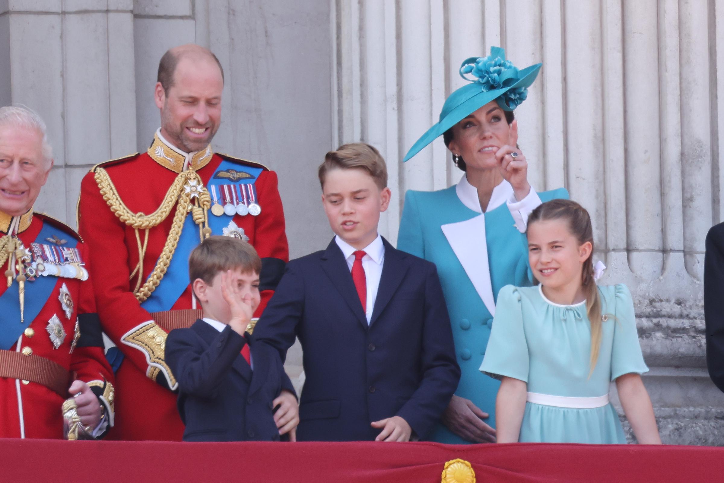Prinz George stupst Prinz Louis sanft an, während König Charles III. und Prinz William neben Prinzessin Catherine und Prinzessin Charlotte lächeln. | Quelle: Getty Images