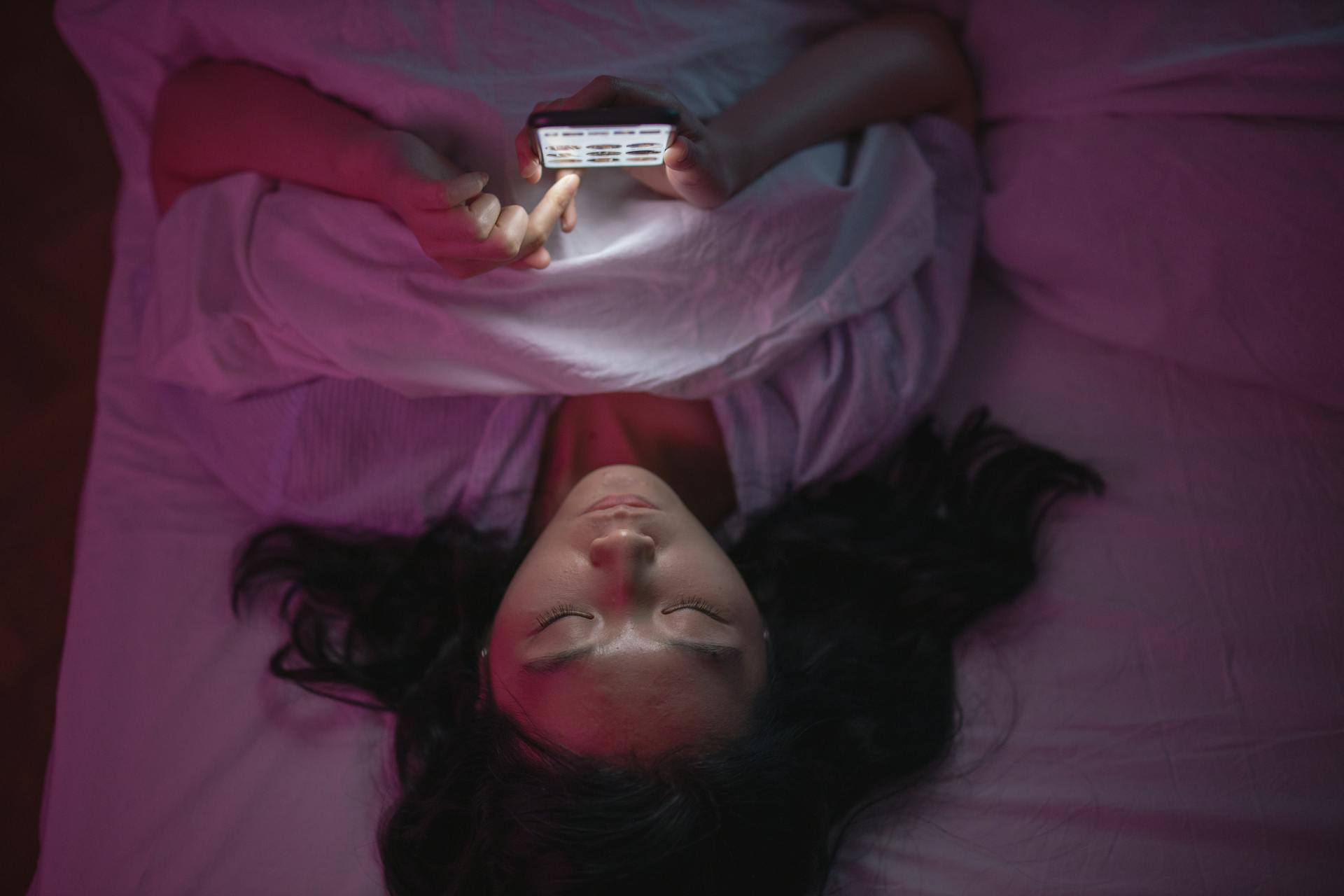 Eine Frau scrollt auf ihrem Handy im Bett | Quelle: Pexels