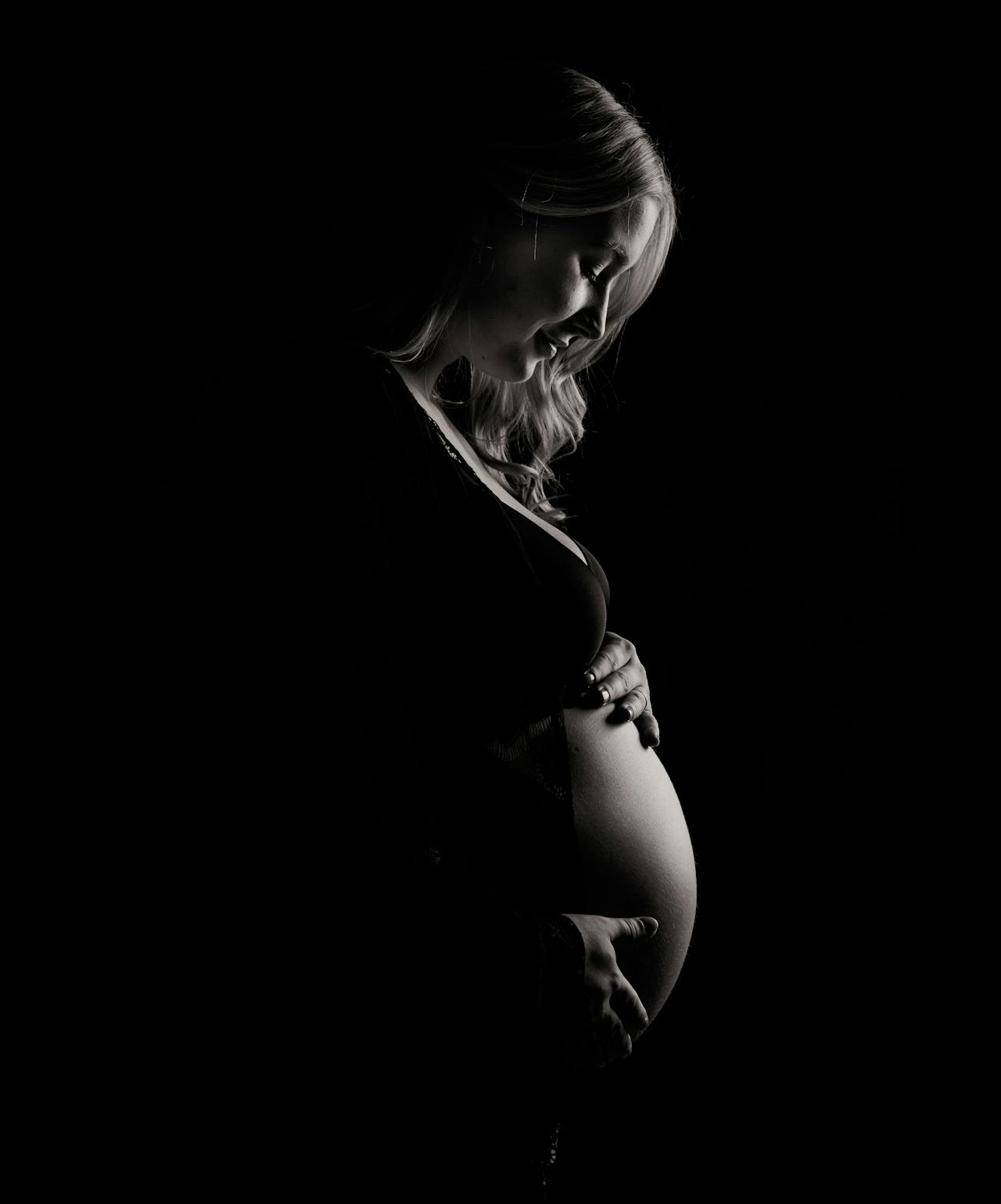 Eine freudige schwangere Frau, die auf ihren Babybauch hinunterschaut | Quelle: Pexels