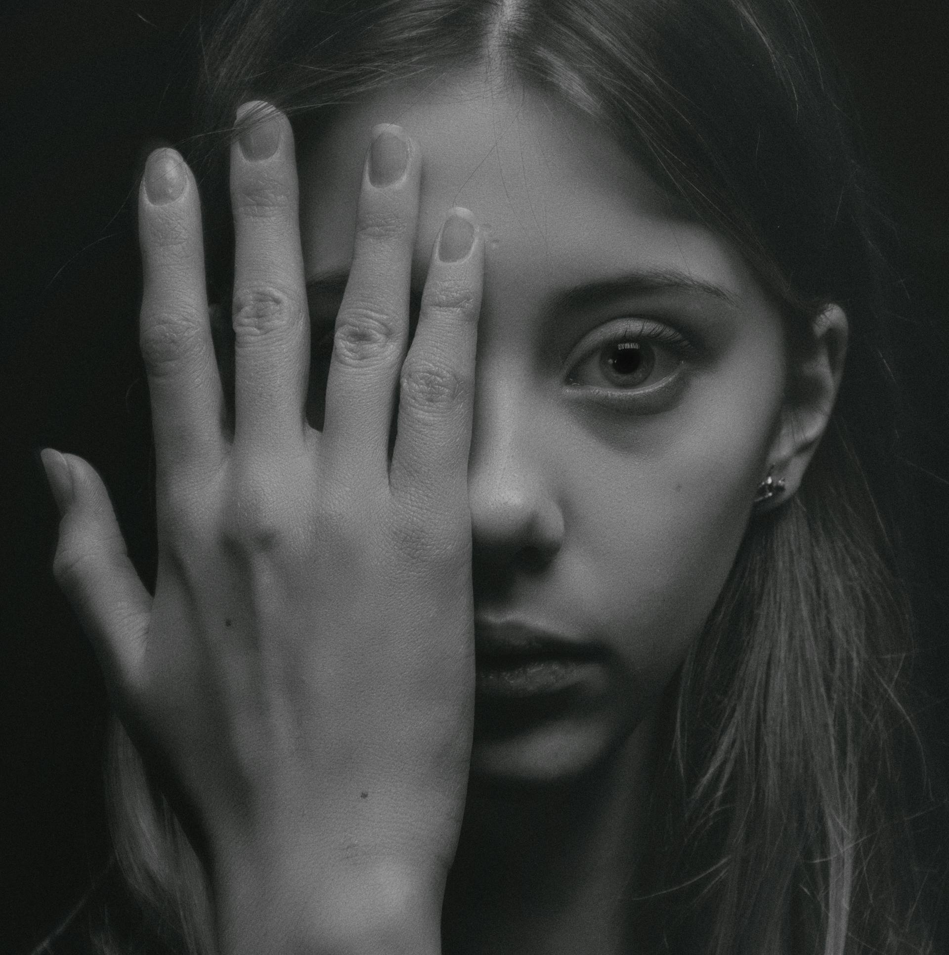 Ein Graustufenfoto einer jungen Frau, das die Hälfte ihres Gesichts verdeckt | Quelle: Pexels