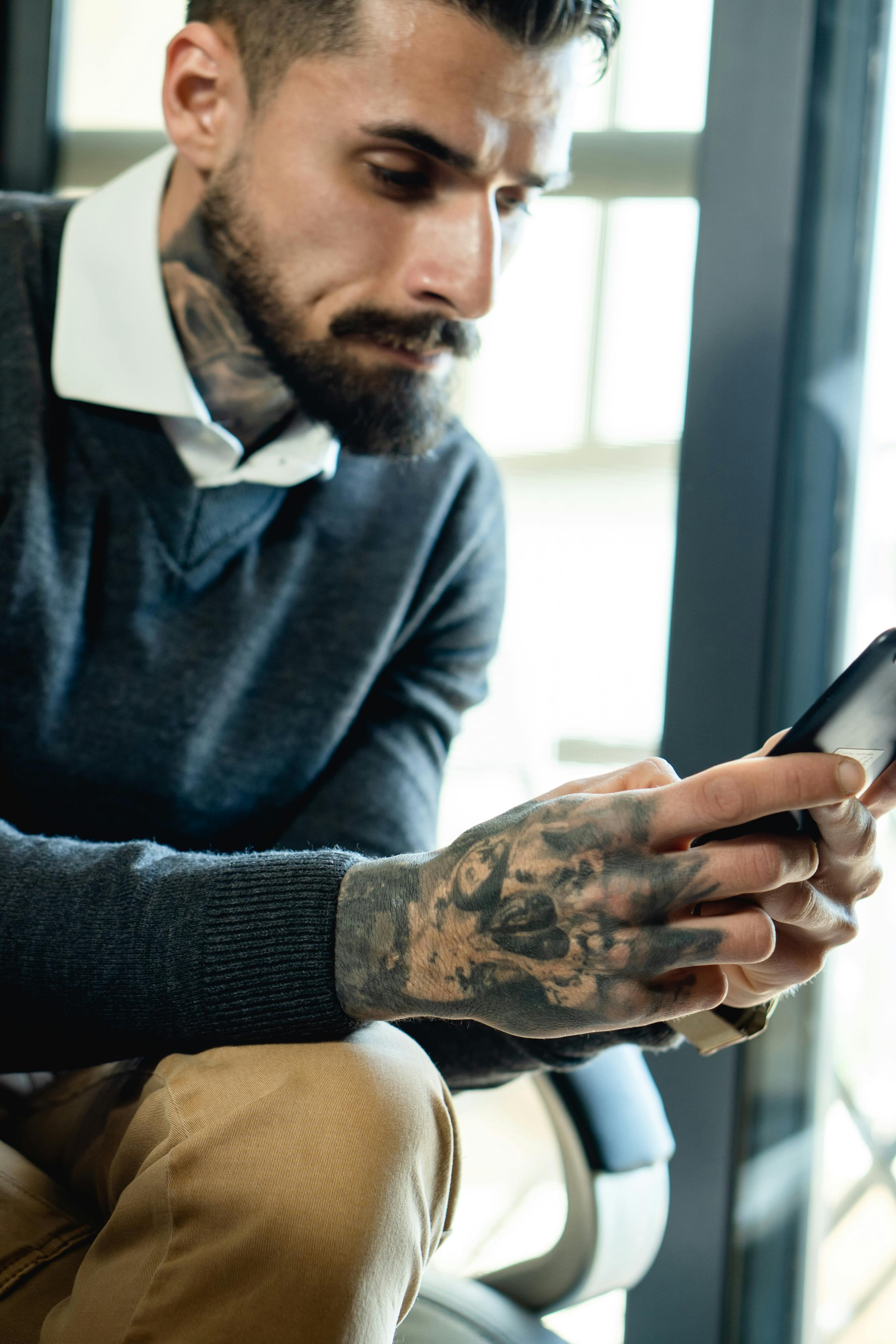 Poważny mężczyzna patrzący na telefon | Źródło: Pexels