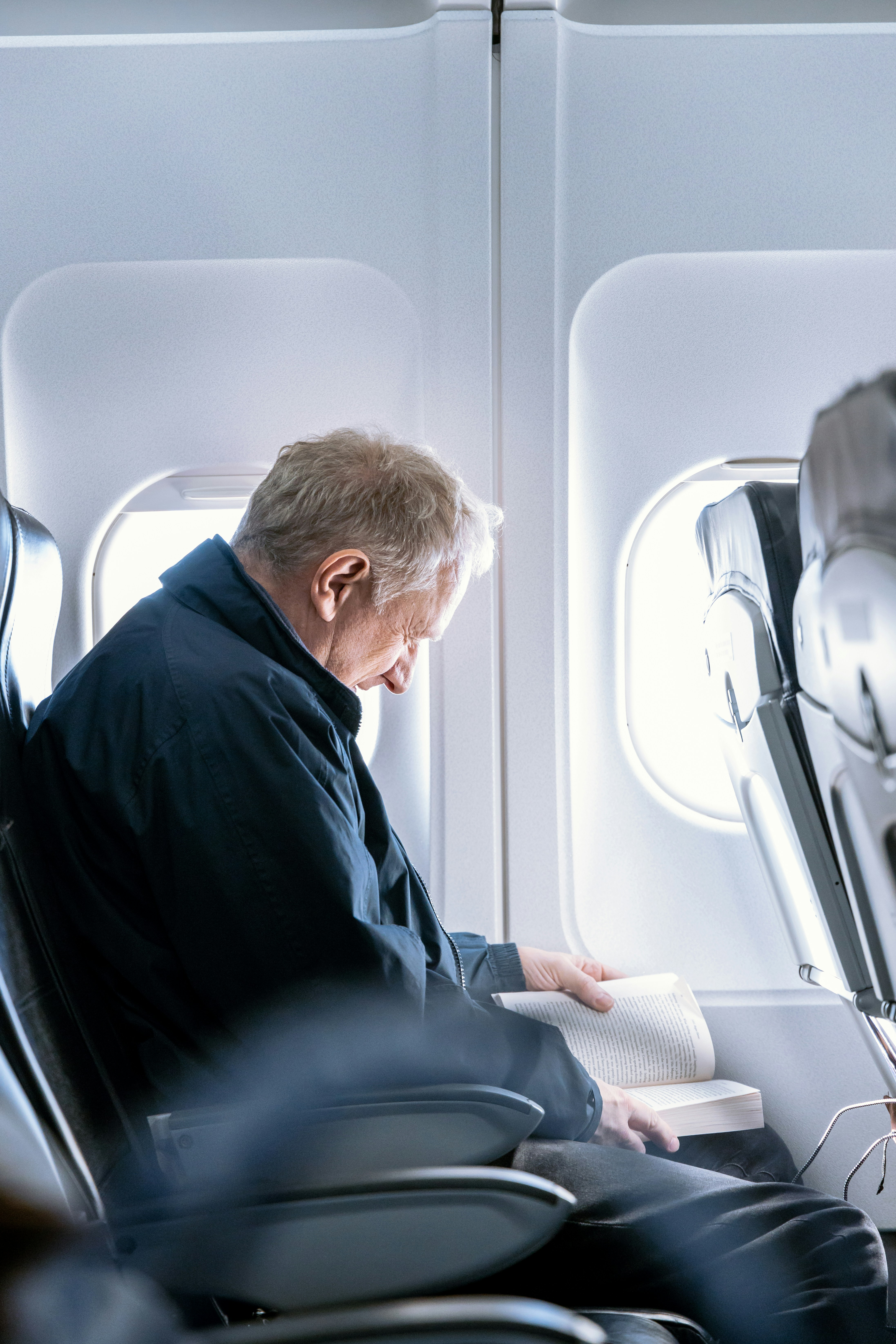 Mann liest ein Buch in einem Flugzeug | Quelle: Unsplash