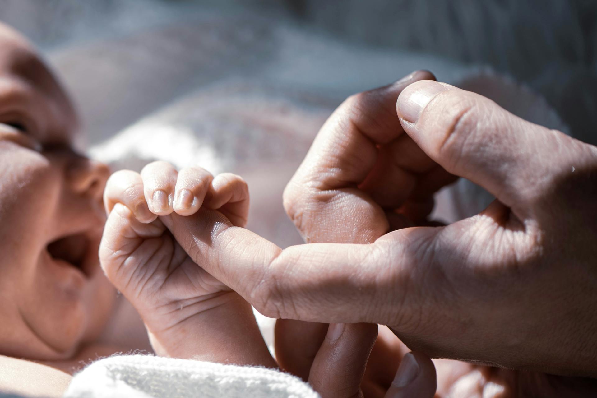 Ein Baby, das den Finger eines Mannes hält | Quelle: Pexels