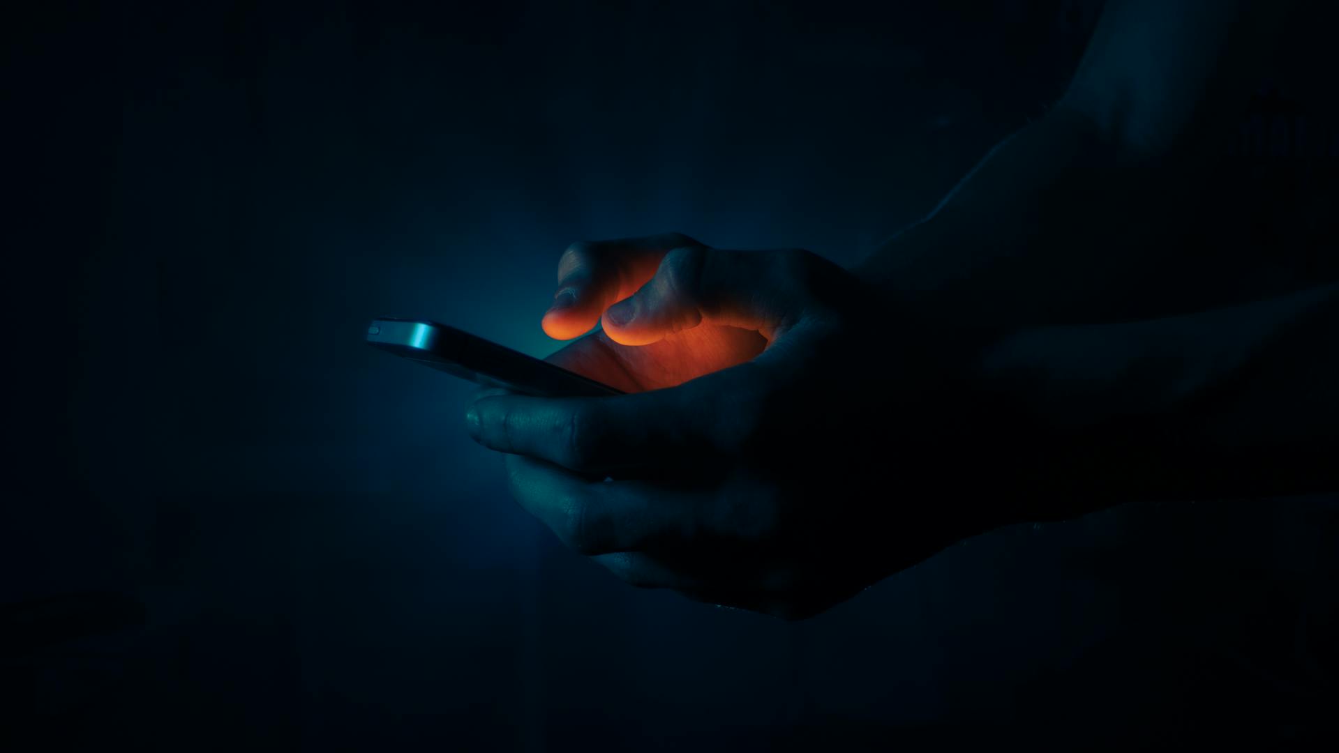 Ein Mann hält ein Telefon in der Dunkelheit | Quelle: Pexels