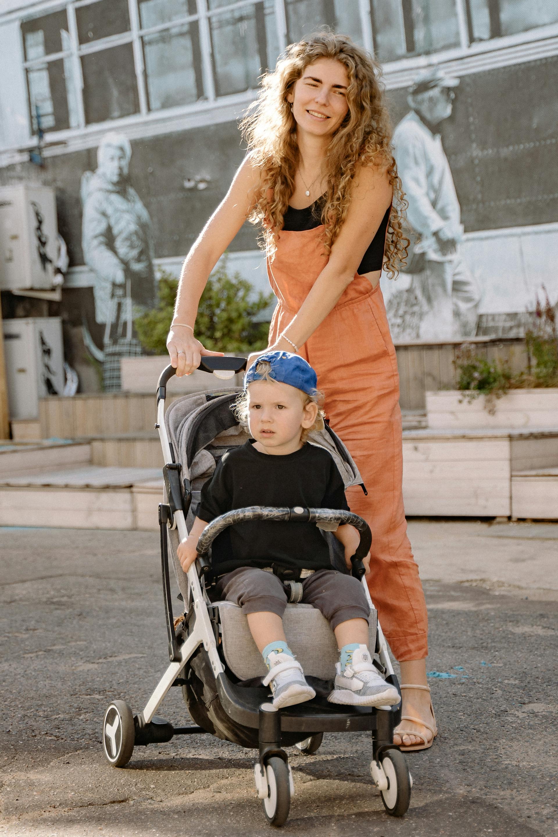 Eine Frau schiebt einen Kinderwagen mit ihrem Sohn darin | Quelle: Pexels