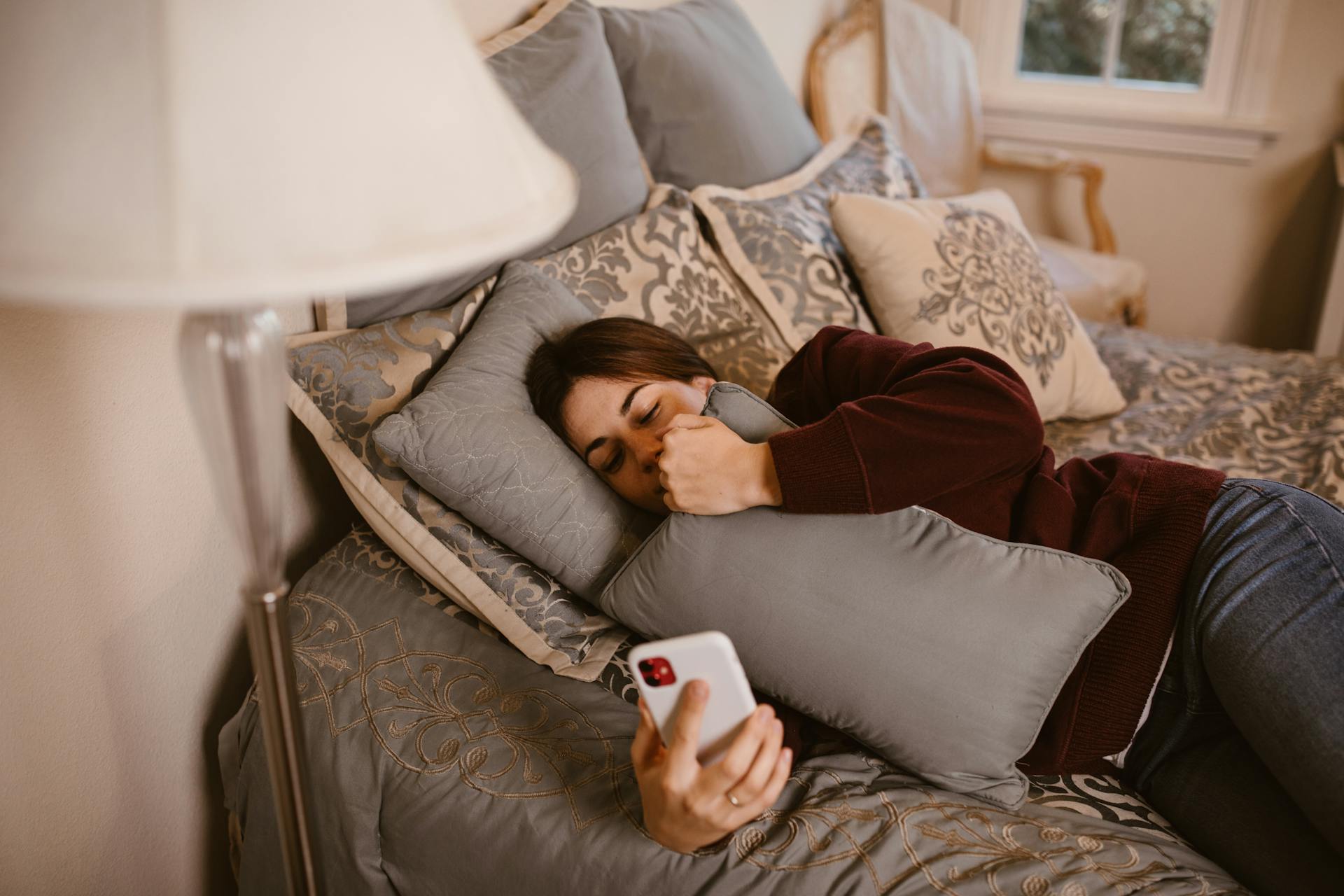 Eine Frau überprüft ihr Smartphone, während sie im Bett liegt | Quelle: Pexels