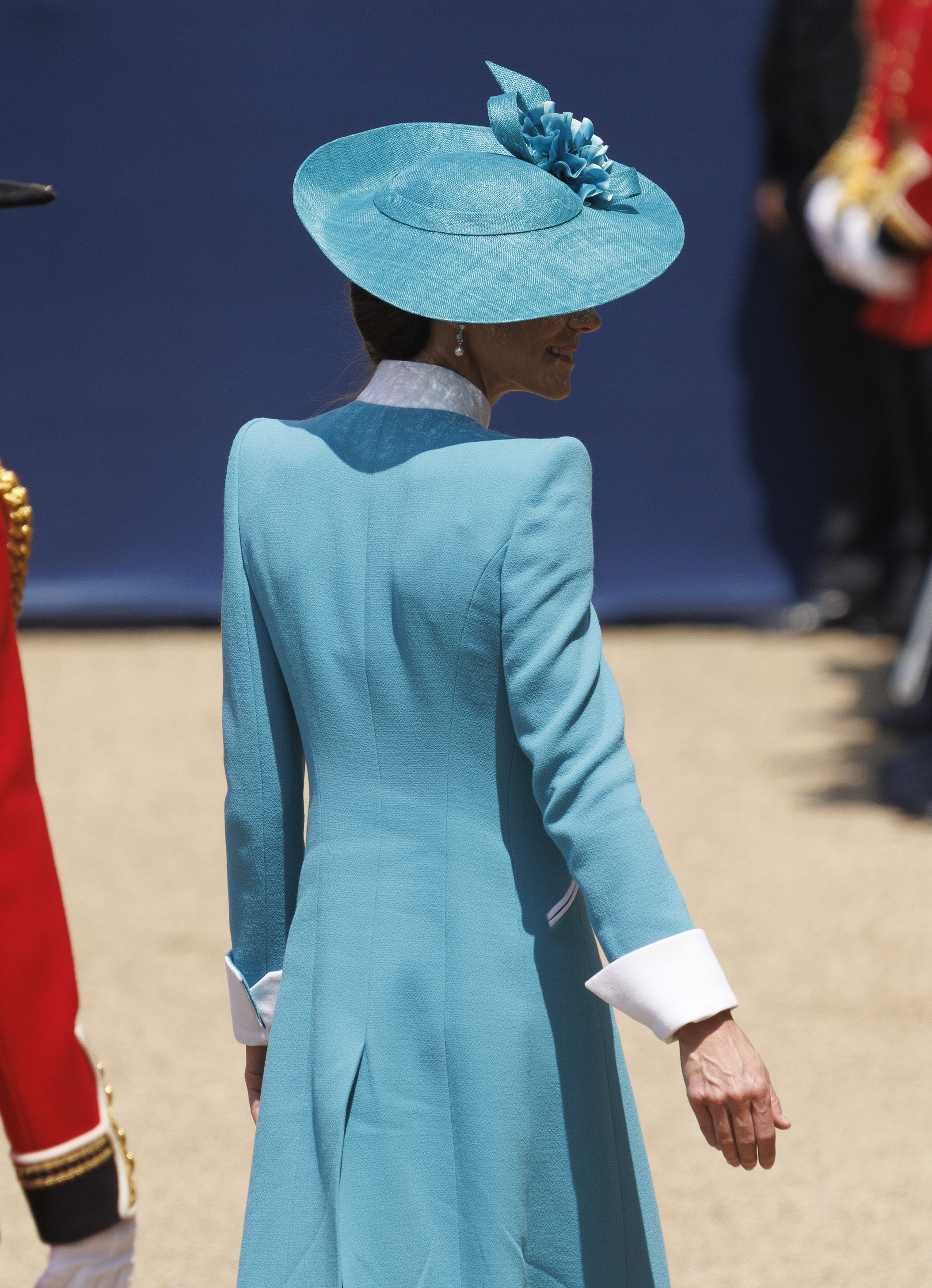 Auf einer Ganzkörperaufnahme vom Trooping the Colour 2025 sieht man Prinzessin Catherine in ihrem auffälligen blaugrünen Mantel mit strahlend weißen Akzenten, während sie sich der feierlichen Parade stellt. Ihr passender Hut und ihre elegante Hochsteckfrisur vervollständigen den Look und sorgen für eine anmutige Silhouette, die sowohl Tradition als auch modernen königlichen Stil widerspiegelt.