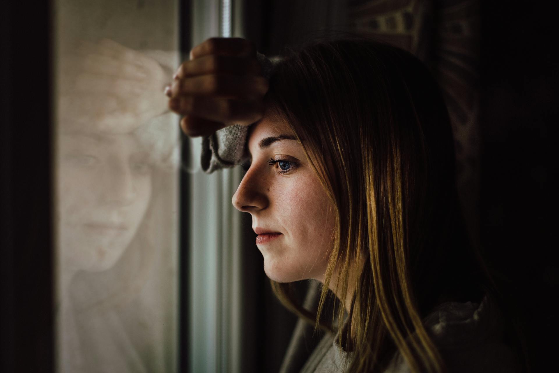 Eine traurige Frau, die sich an ein Glasfenster lehnt | Quelle: Pexels
