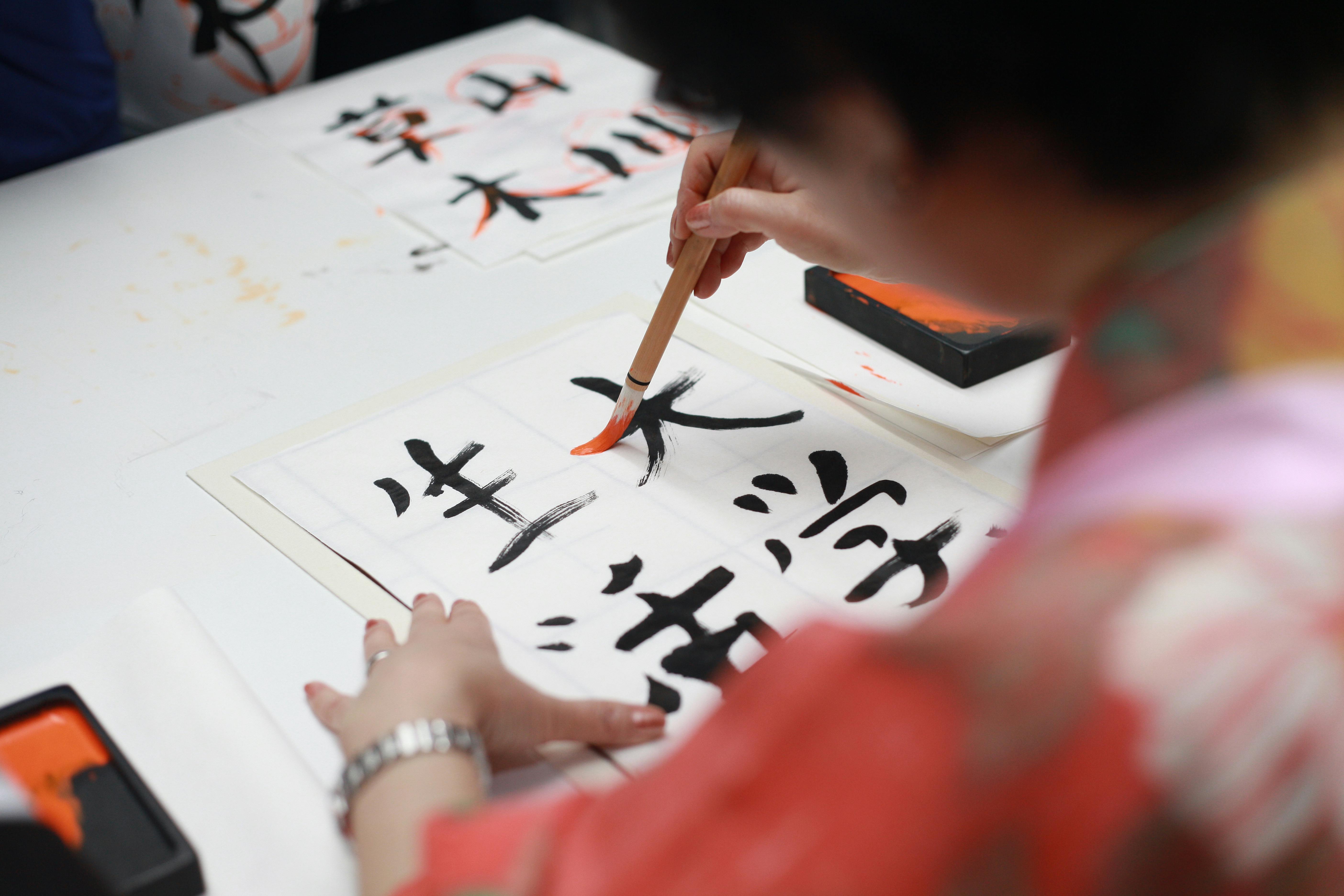 Eine Person hält einen Pinsel und zeichnet Kanji-Schrift | Quelle: Pexels