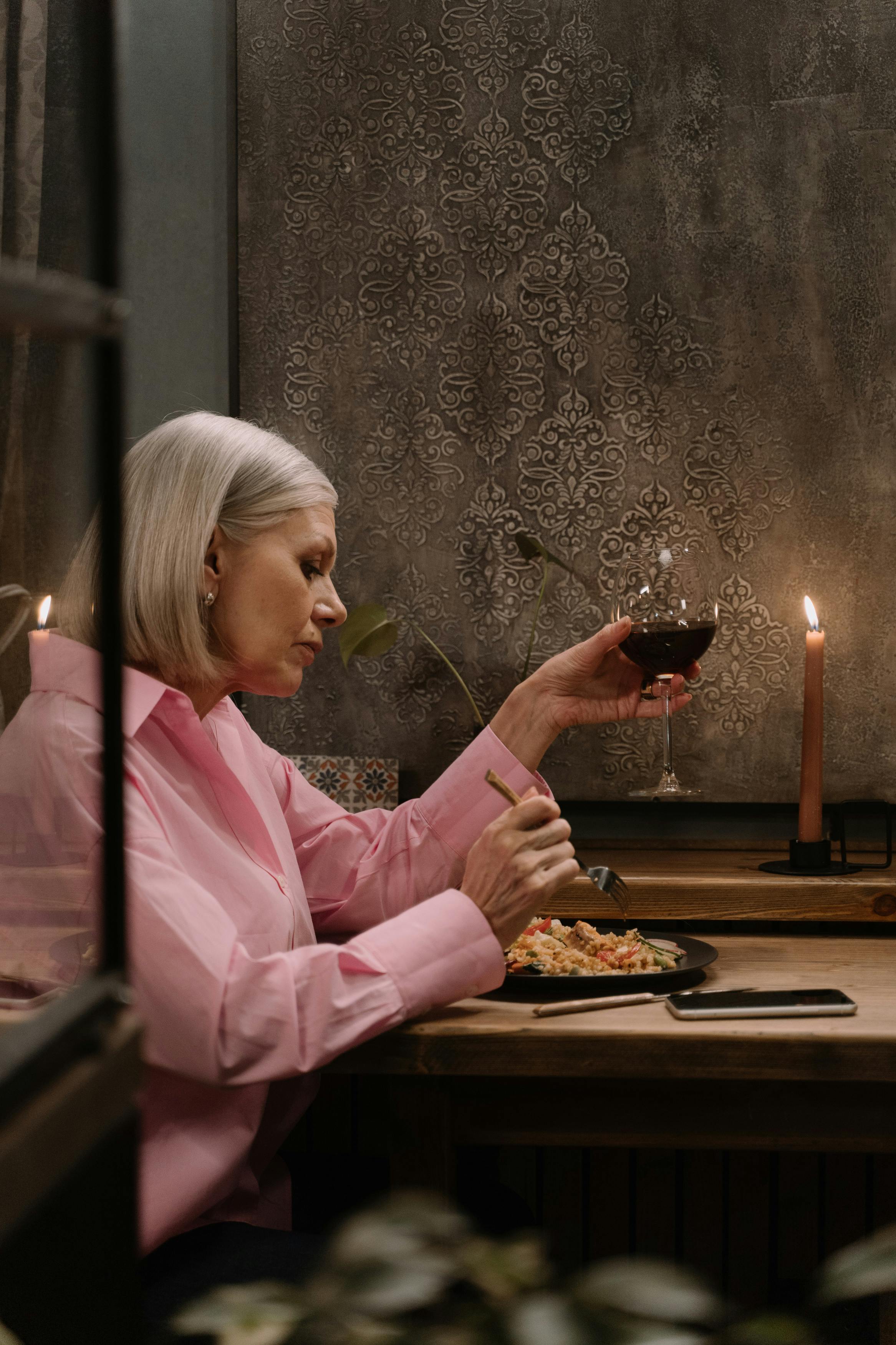Frau hält ein Glas Wein, während sie isst | Quelle: Pexels