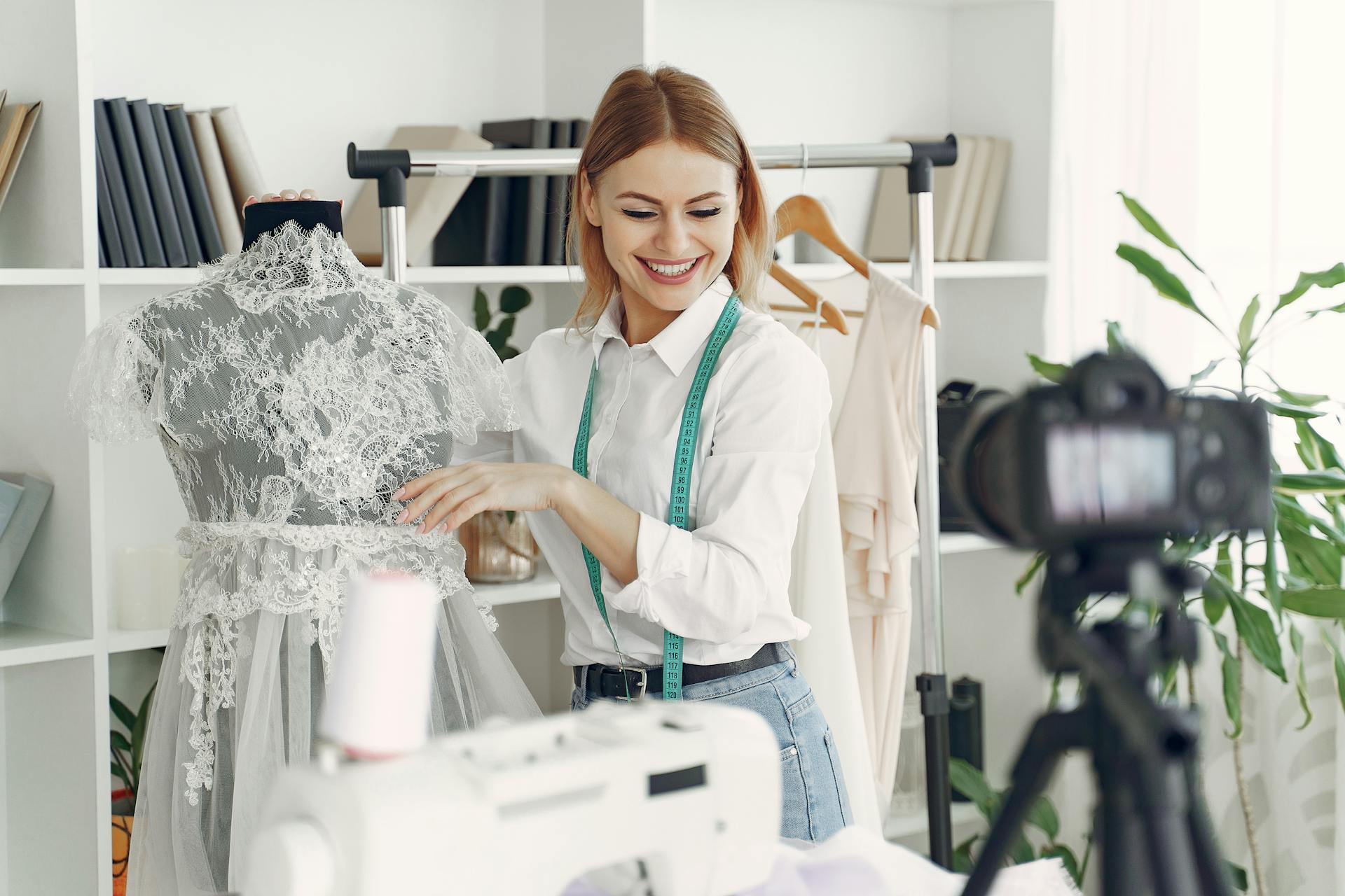 Eine glückliche Schneiderin steht neben einem Brautkleid in ihrem Laden | Quelle: Pexels