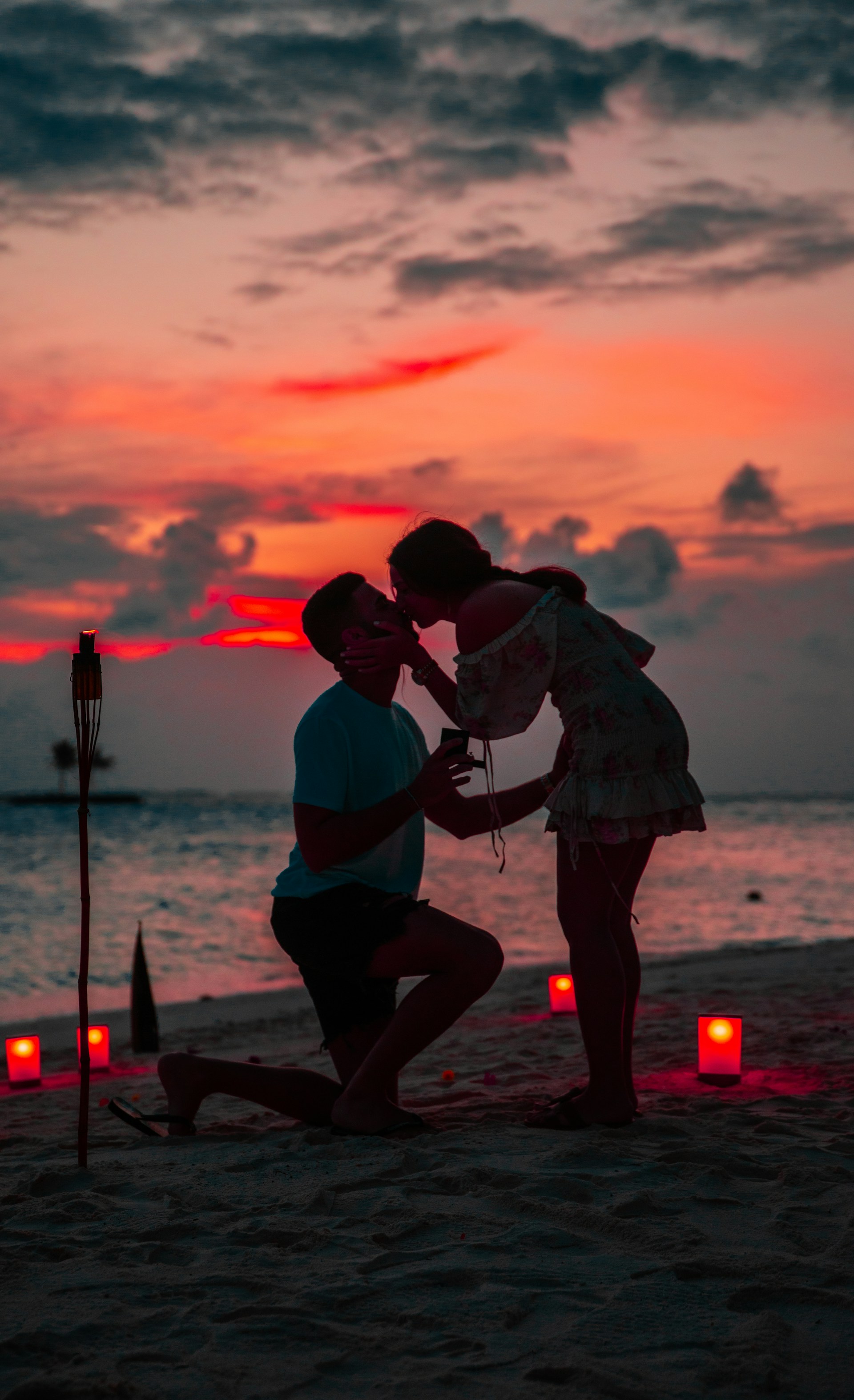 Ein Mann auf einem Knie mit einem Ring, während seine Partnerin ihn küsst | Quelle: Unsplash