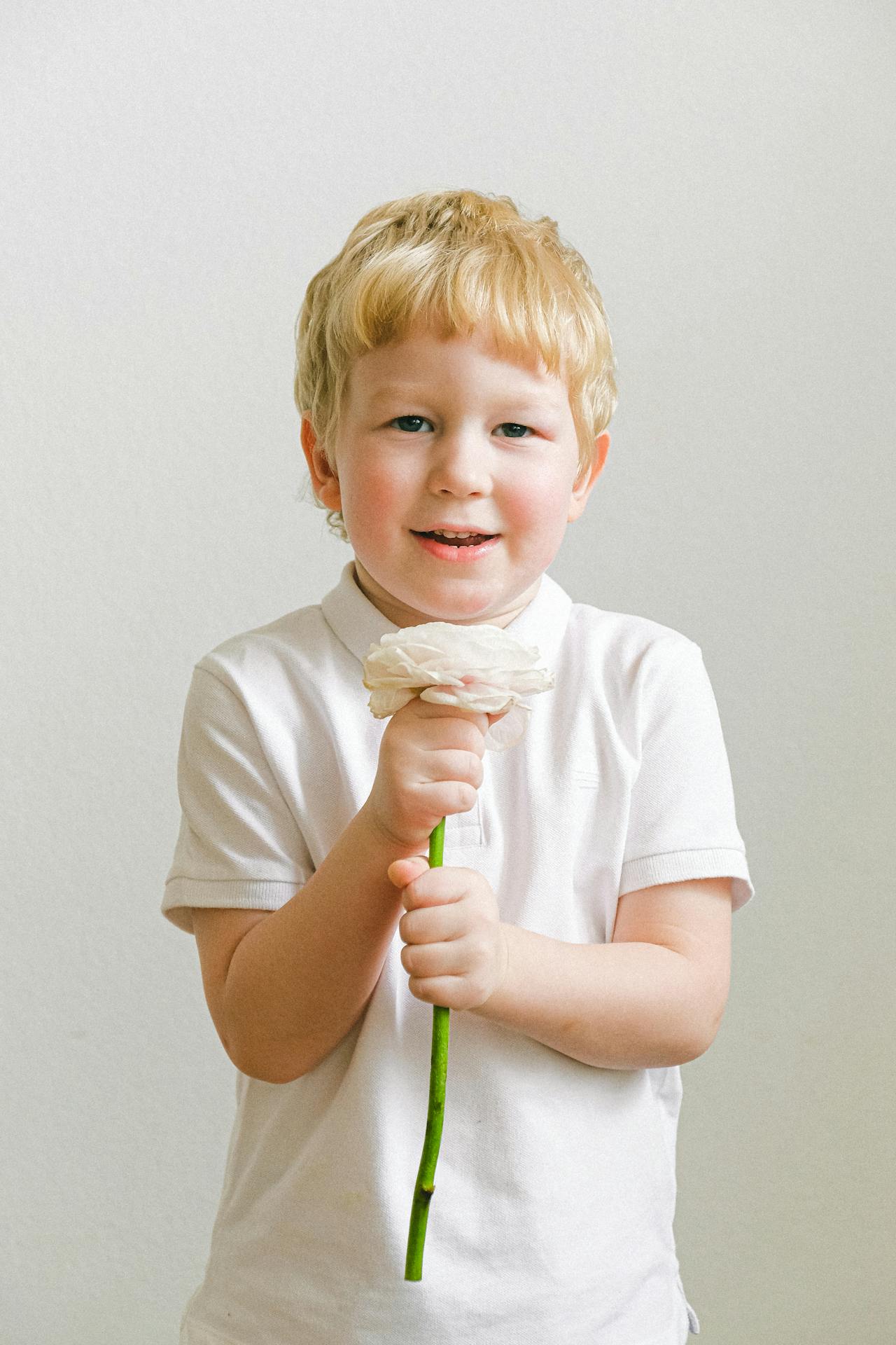 Ein aufgeregter kleiner Junge hält eine Blume | Quelle: Pexels