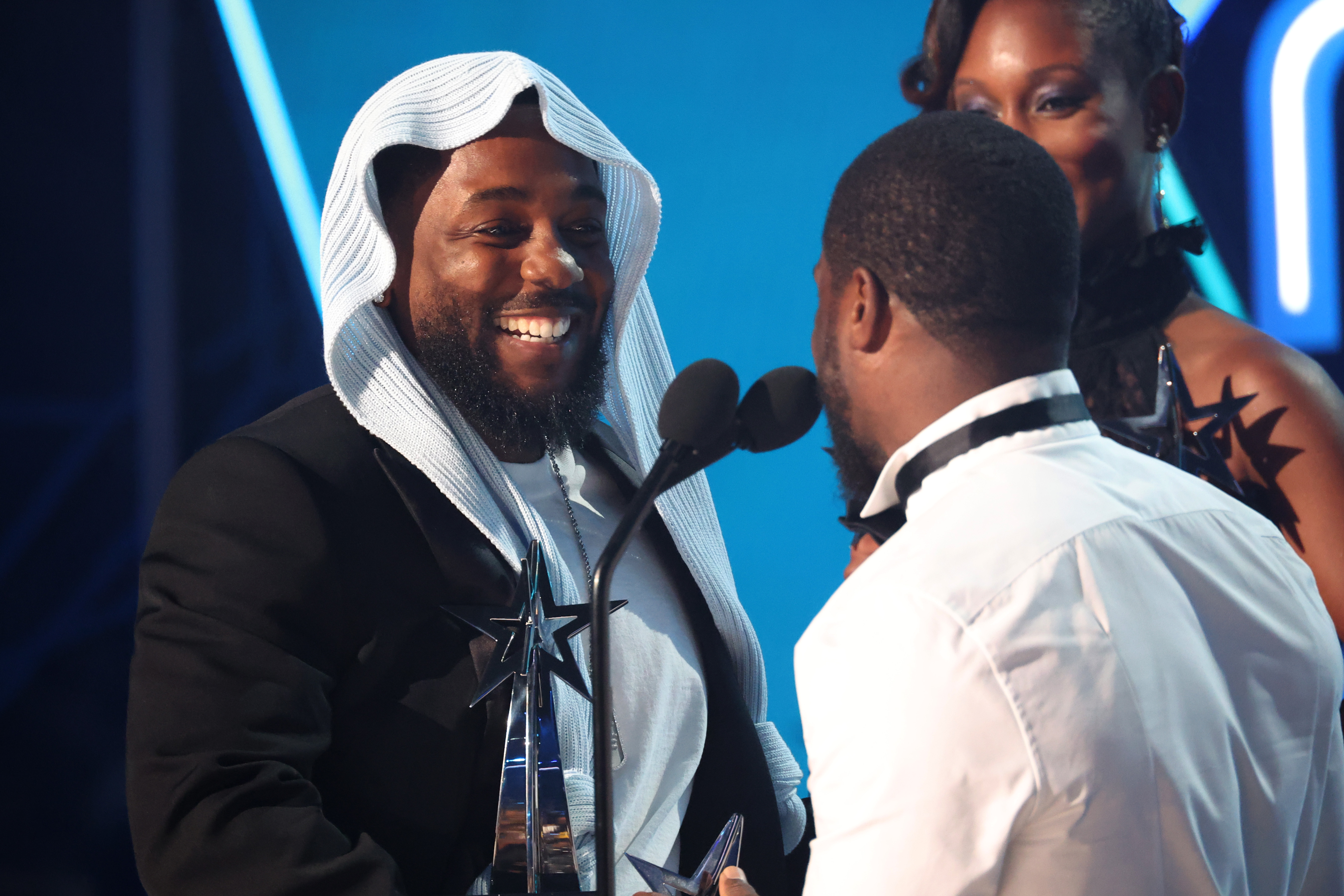 Kendrick Lamar lacht mit Kevin Hart während eines lustigen Moments auf der Bühne bei den BET Awards 2025. Umgeben von seinen Künstlerkollegen sorgten die Kameradschaft der beiden und Lamars beeindruckende Anzahl an Auszeichnungen für einen heiteren Moment.