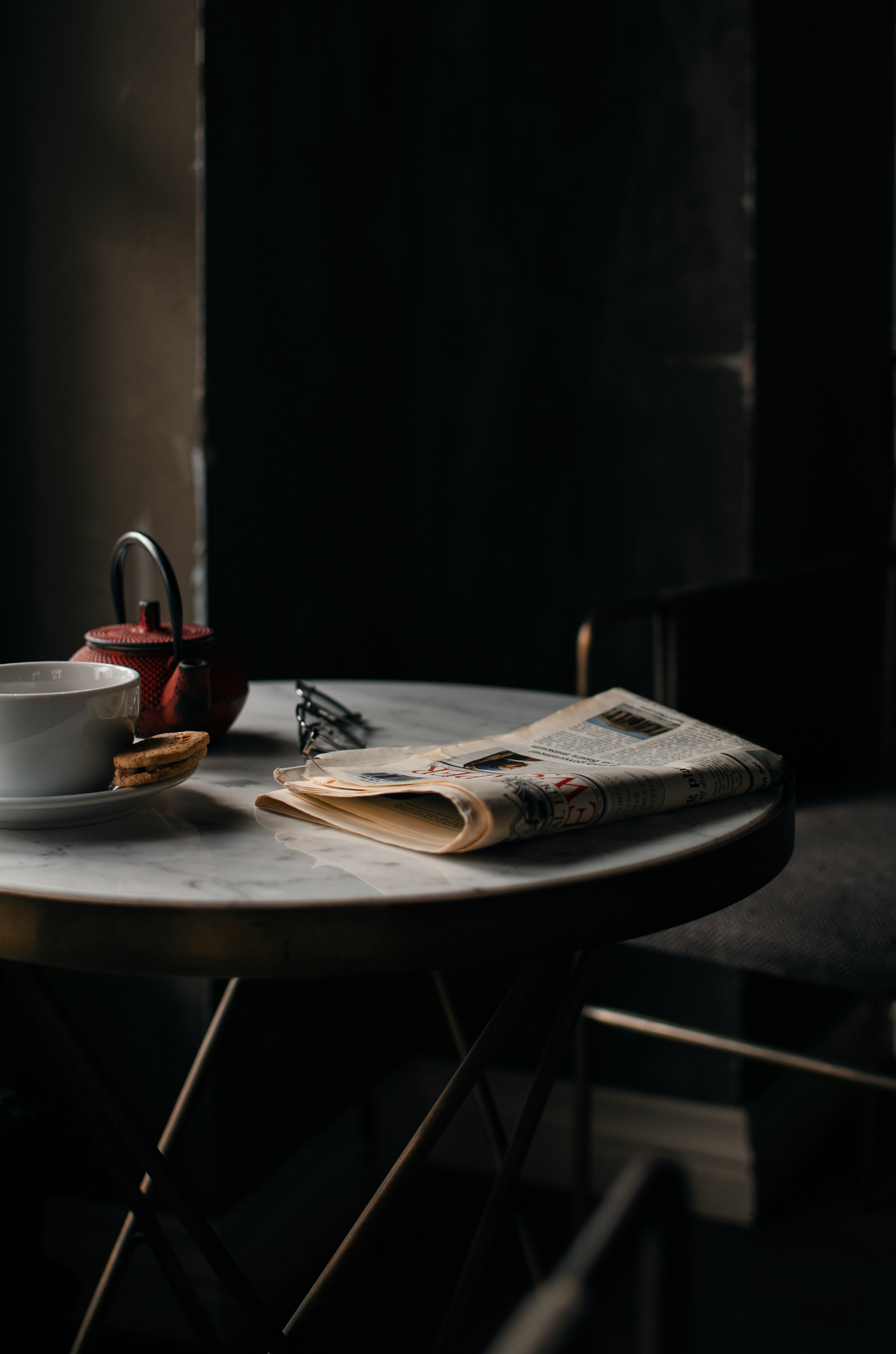 Ein Wasserkocher und eine Kaffeetasse neben einer ordentlich gefalteten Zeitung | Quelle: Unsplash