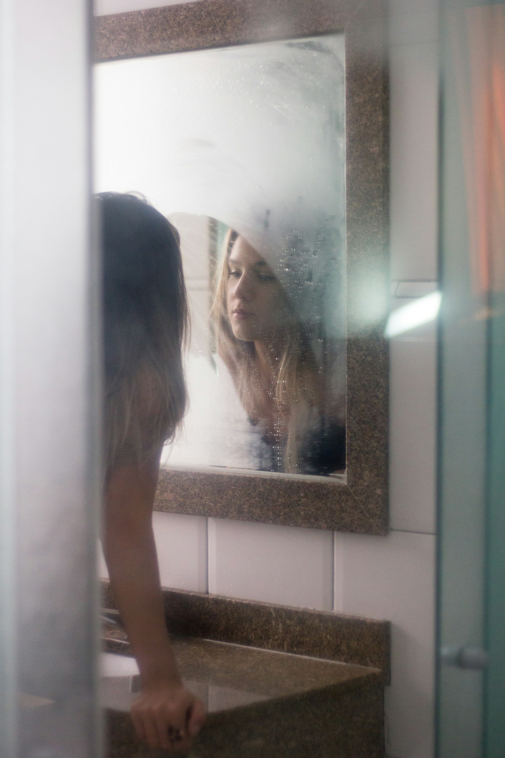 Eine Frau, die sich in einem Badezimmerspiegel betrachtet | Quelle: Unsplash