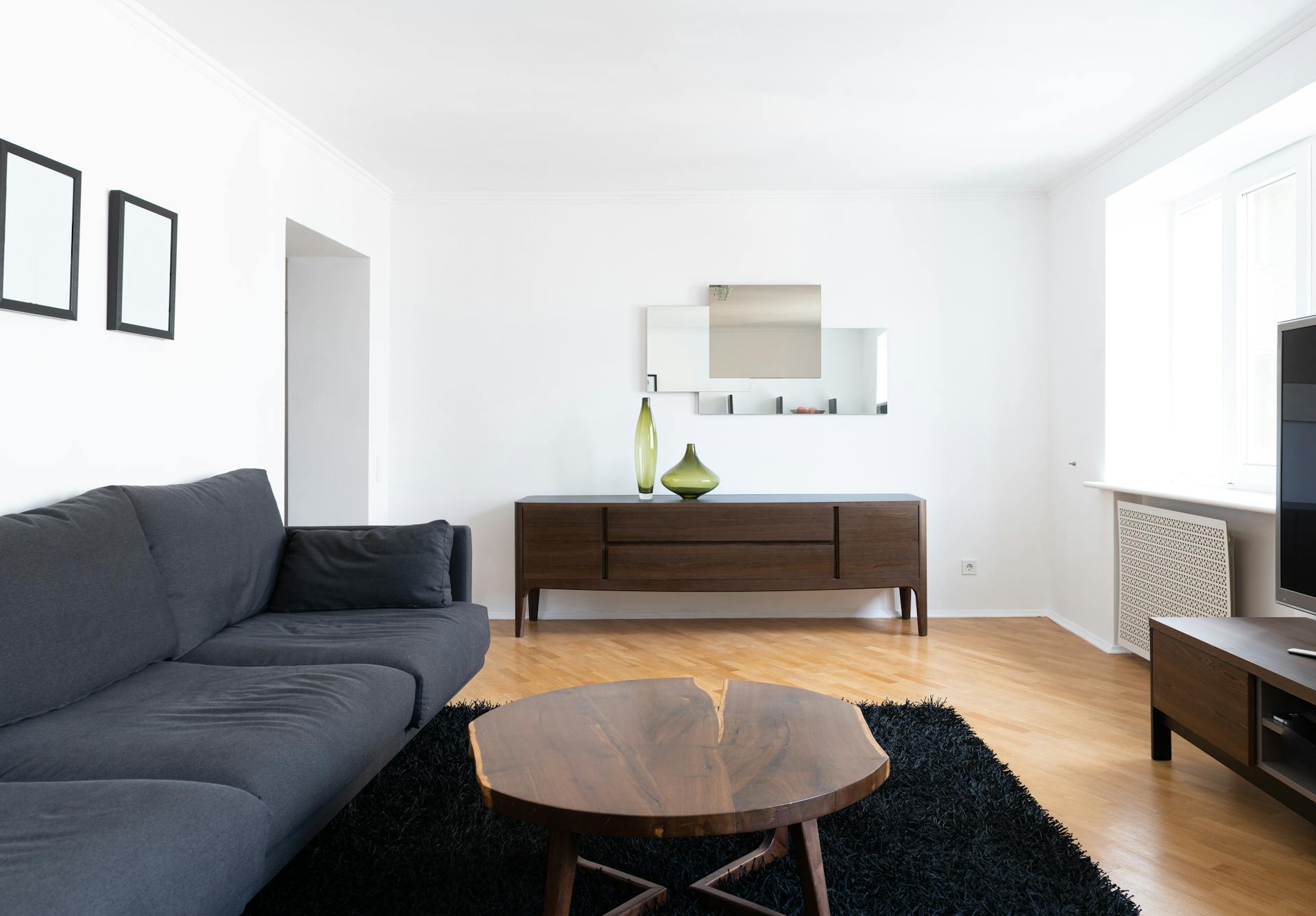 Ein sauberes Wohnzimmer mit einer schwarzen Couch, einem Couchtisch aus Holz und einem braunen Schrank | Quelle: Pexels