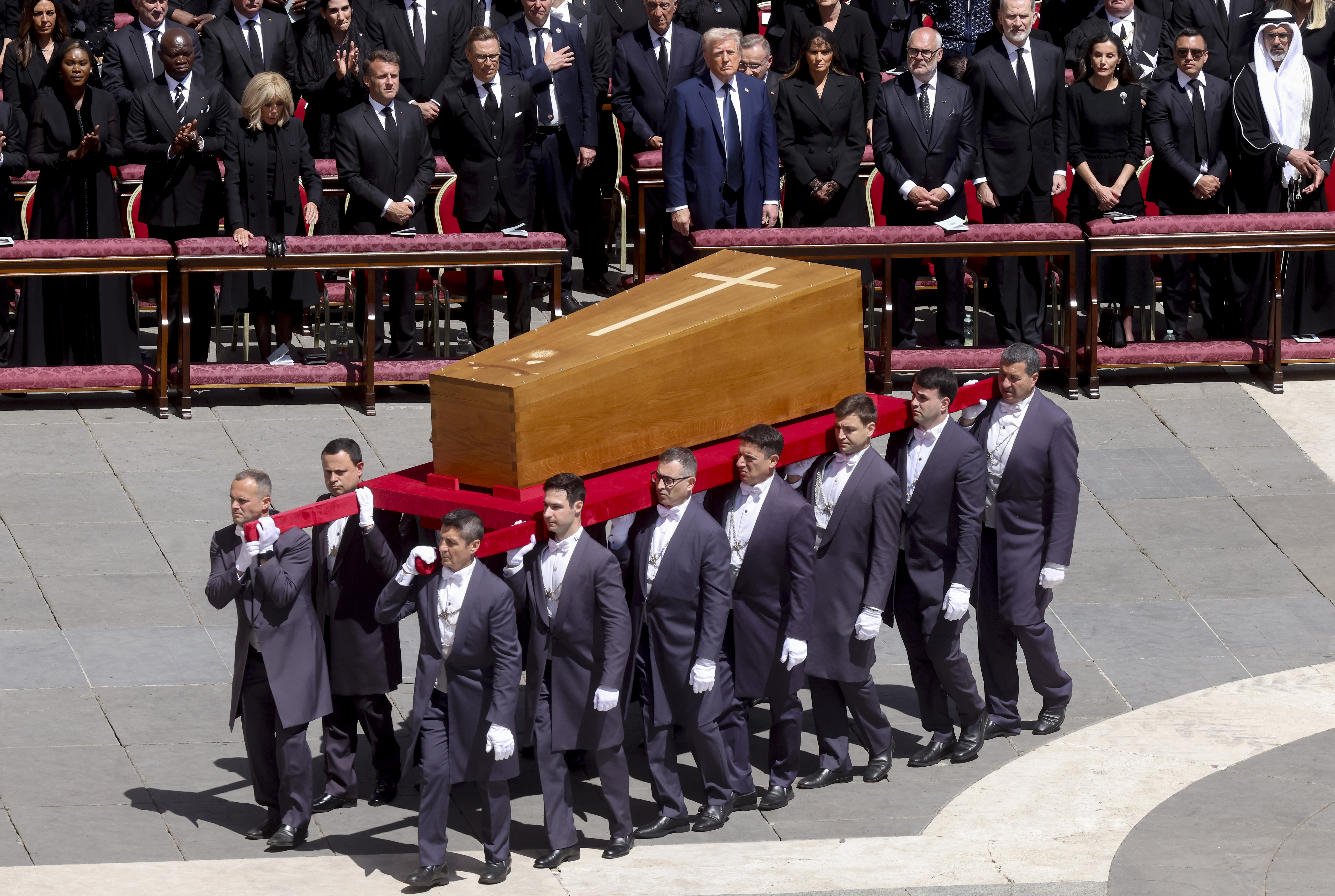 Während der Sarg langsam den Petersplatz verlässt, stehen die First Lady Frankreichs, Brigitte Macron, Frankreichs Präsident Emmanuel Macron, Melania, Donald, König Felipe und Königin Letizia von Spanien in stiller Andacht, ihre Gesichter gezeichnet von der Schwere des Augenblicks, während sie die kollektive Trauer teilen.
