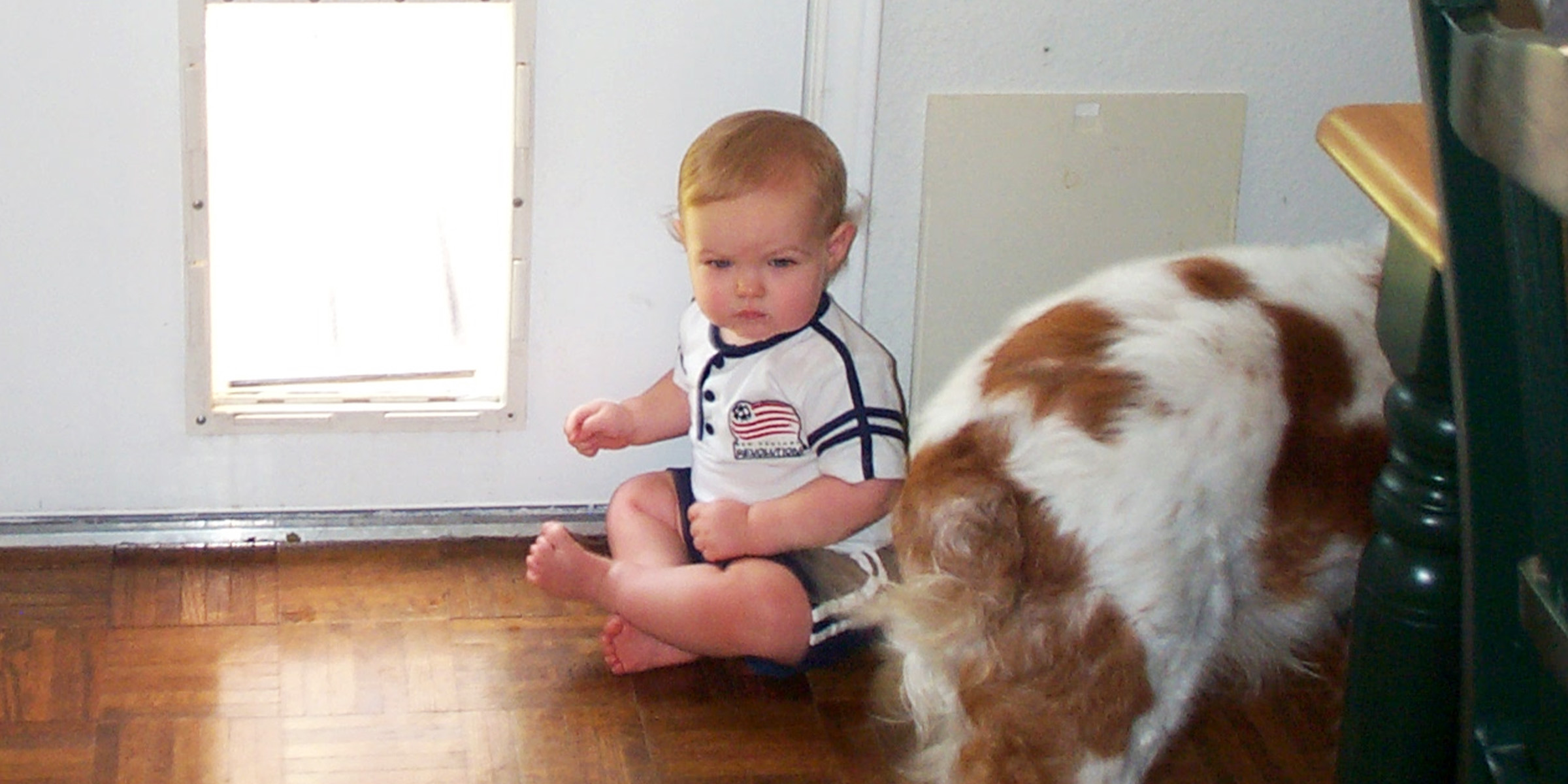 Ein Kind sitzt neben einer Hundetür | Quelle: Flickr